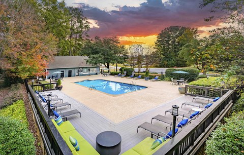 A beautiful outdoor swimming pool area with lounge chairs and a sunset view.