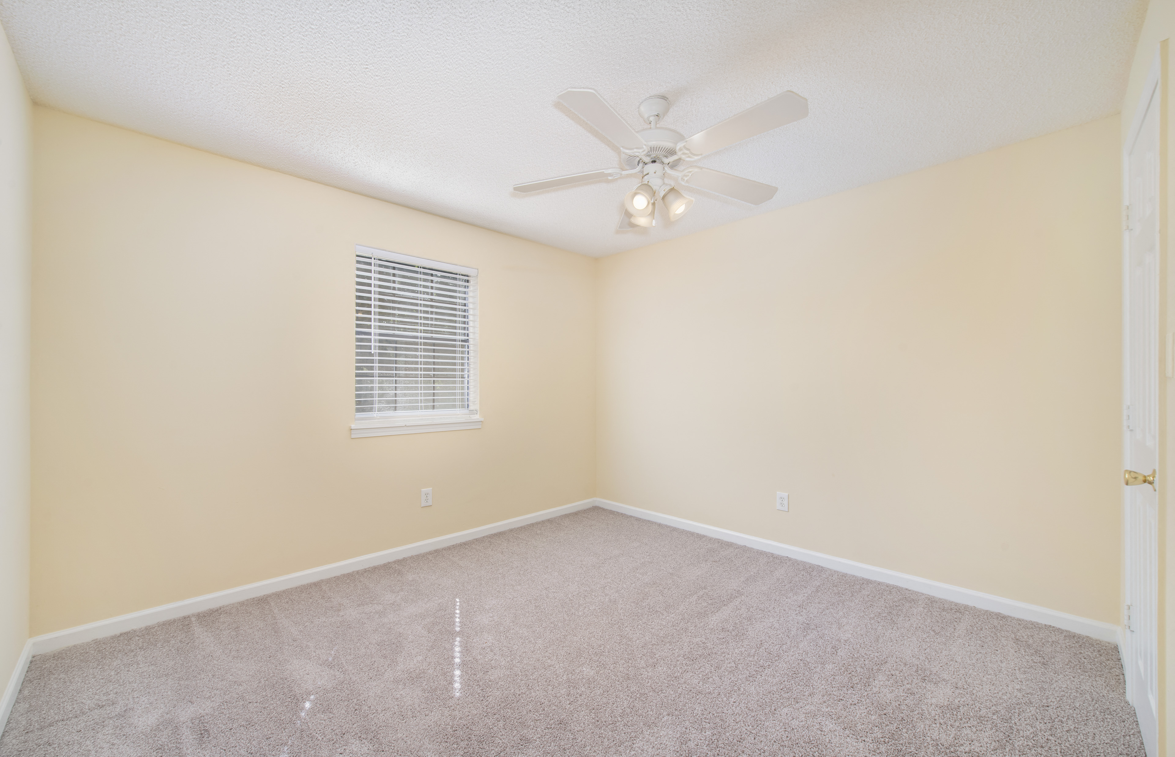 an empty living room with a ceiling fan and a window