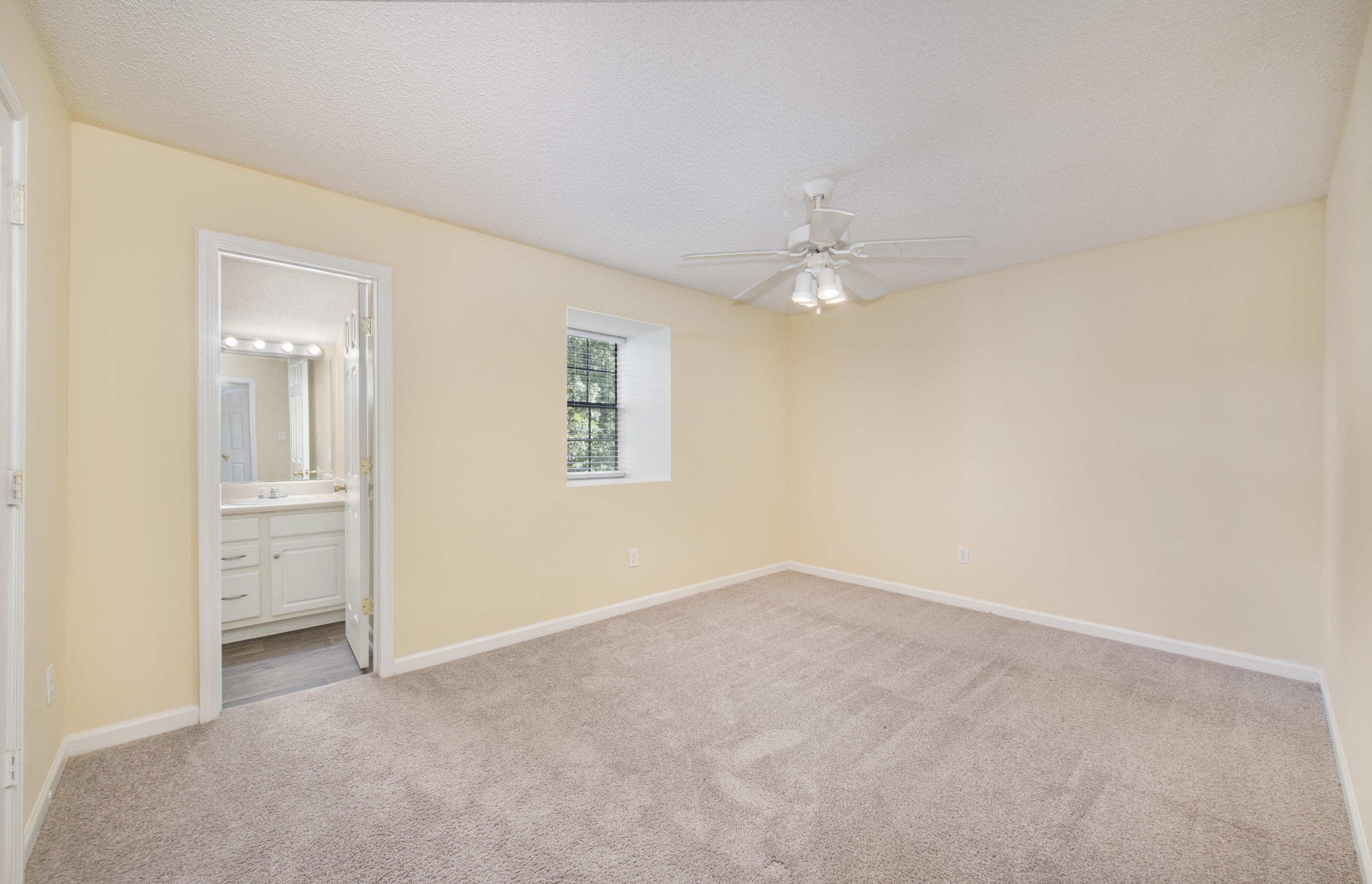 an empty living room with carpet and a ceiling fan