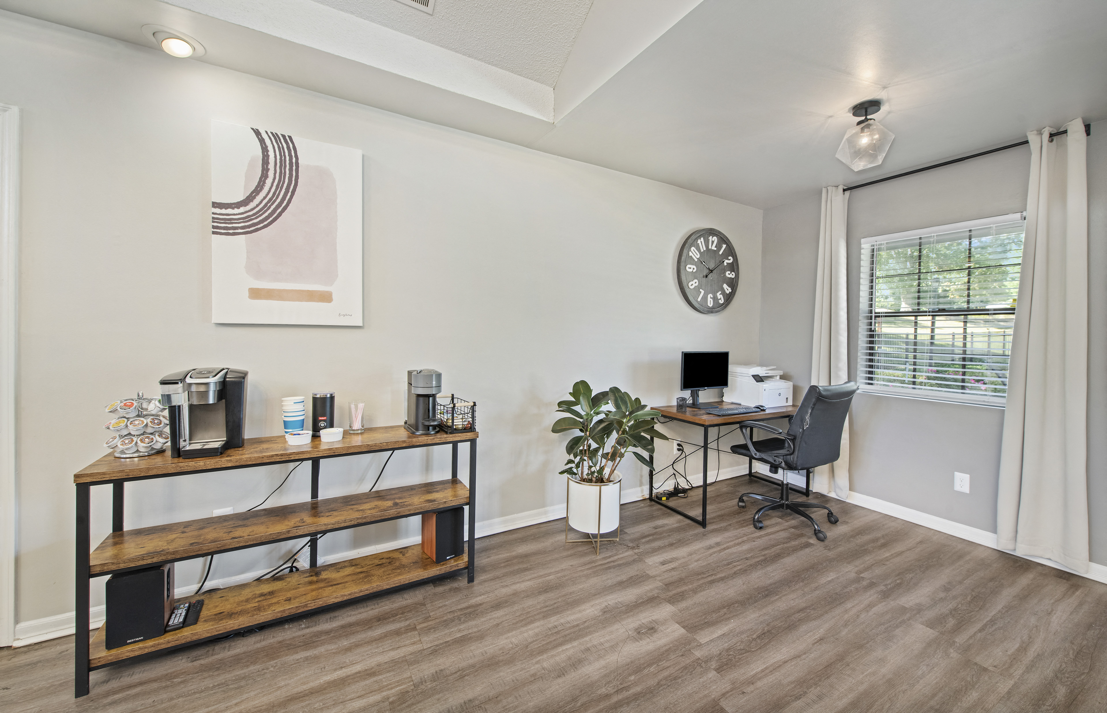 an office with a desk and a clock on the wall and a window