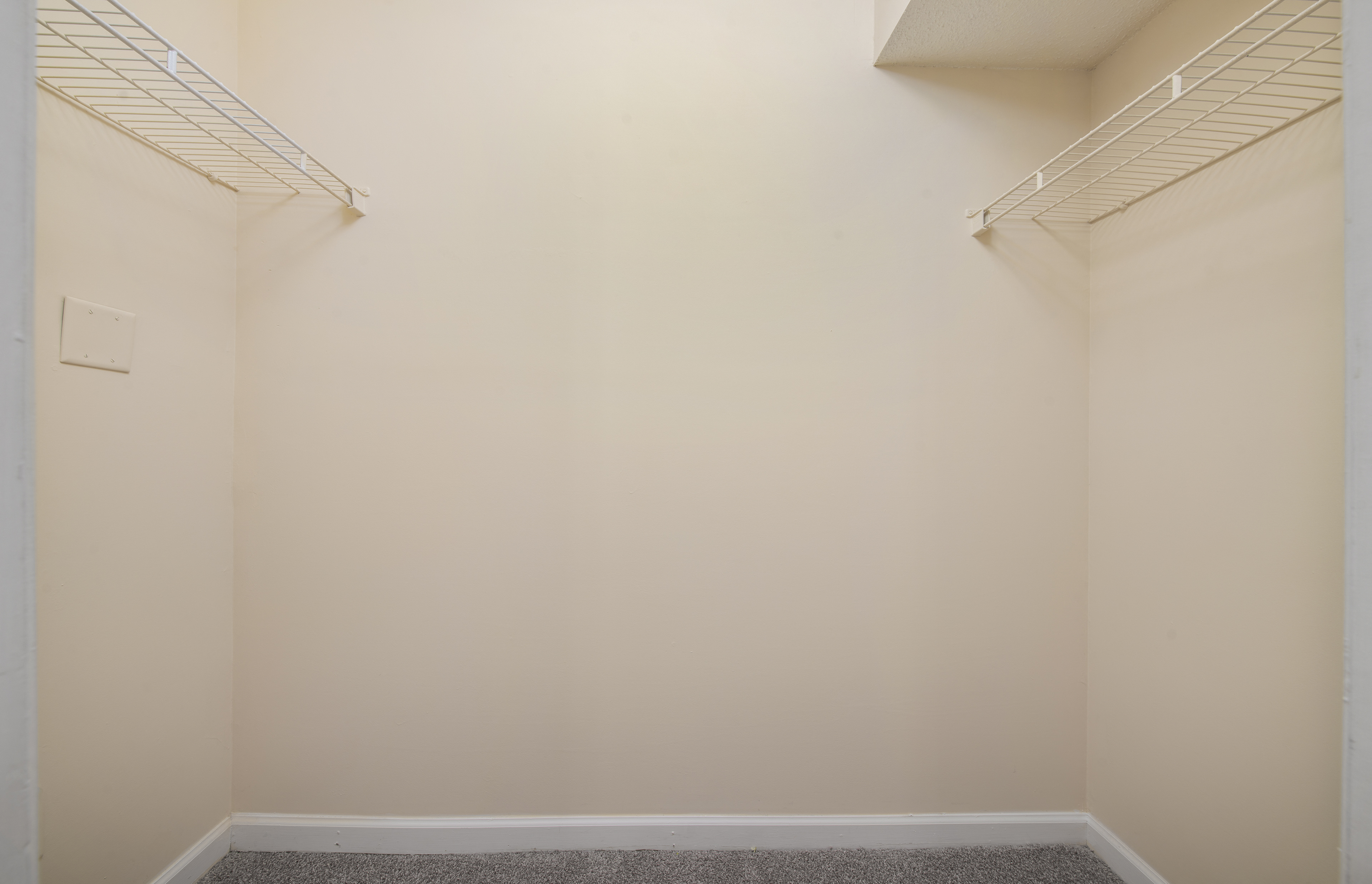an empty room with white walls and a shelf on the wall