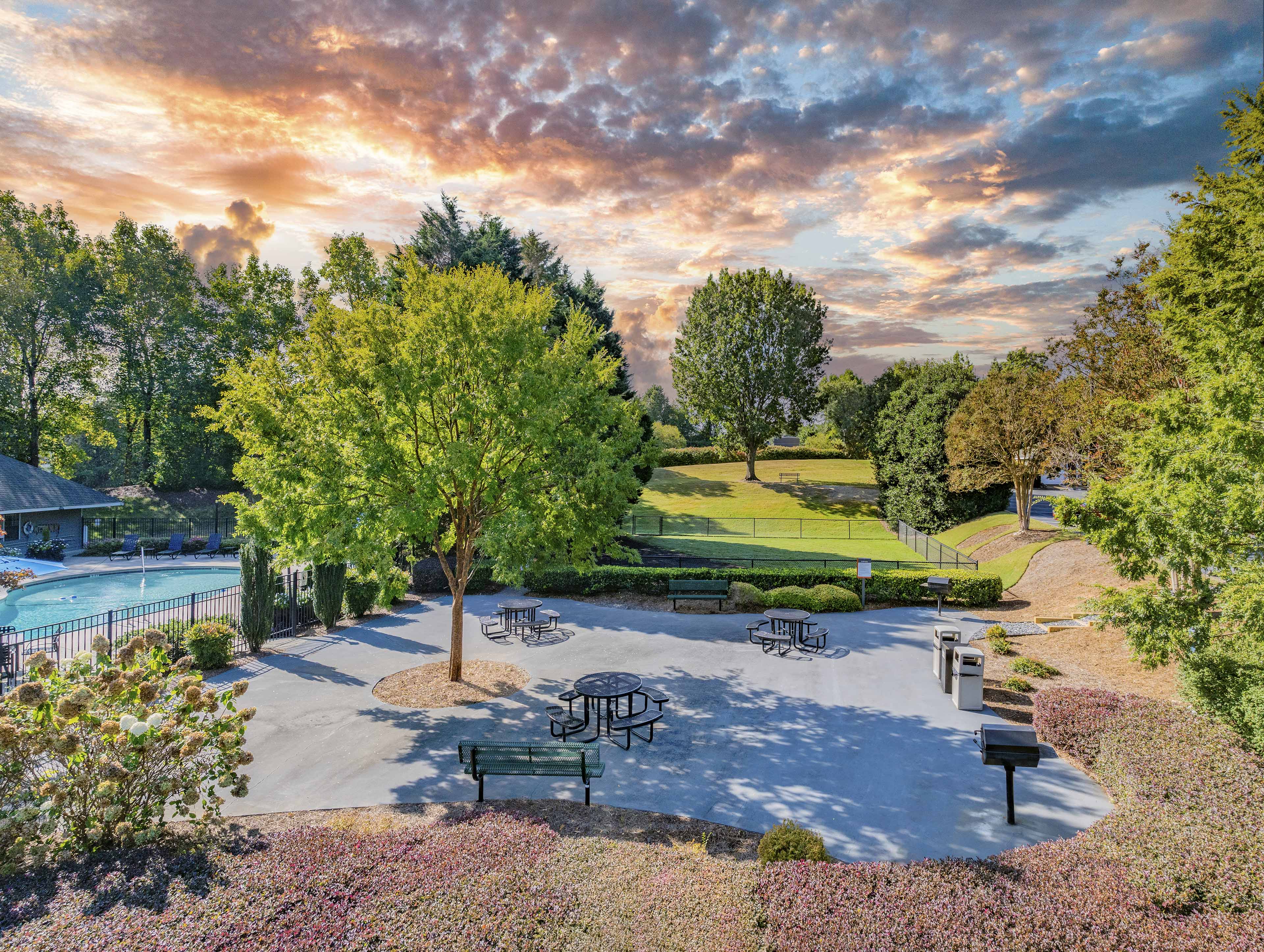 a park with benches and a pool at sunset