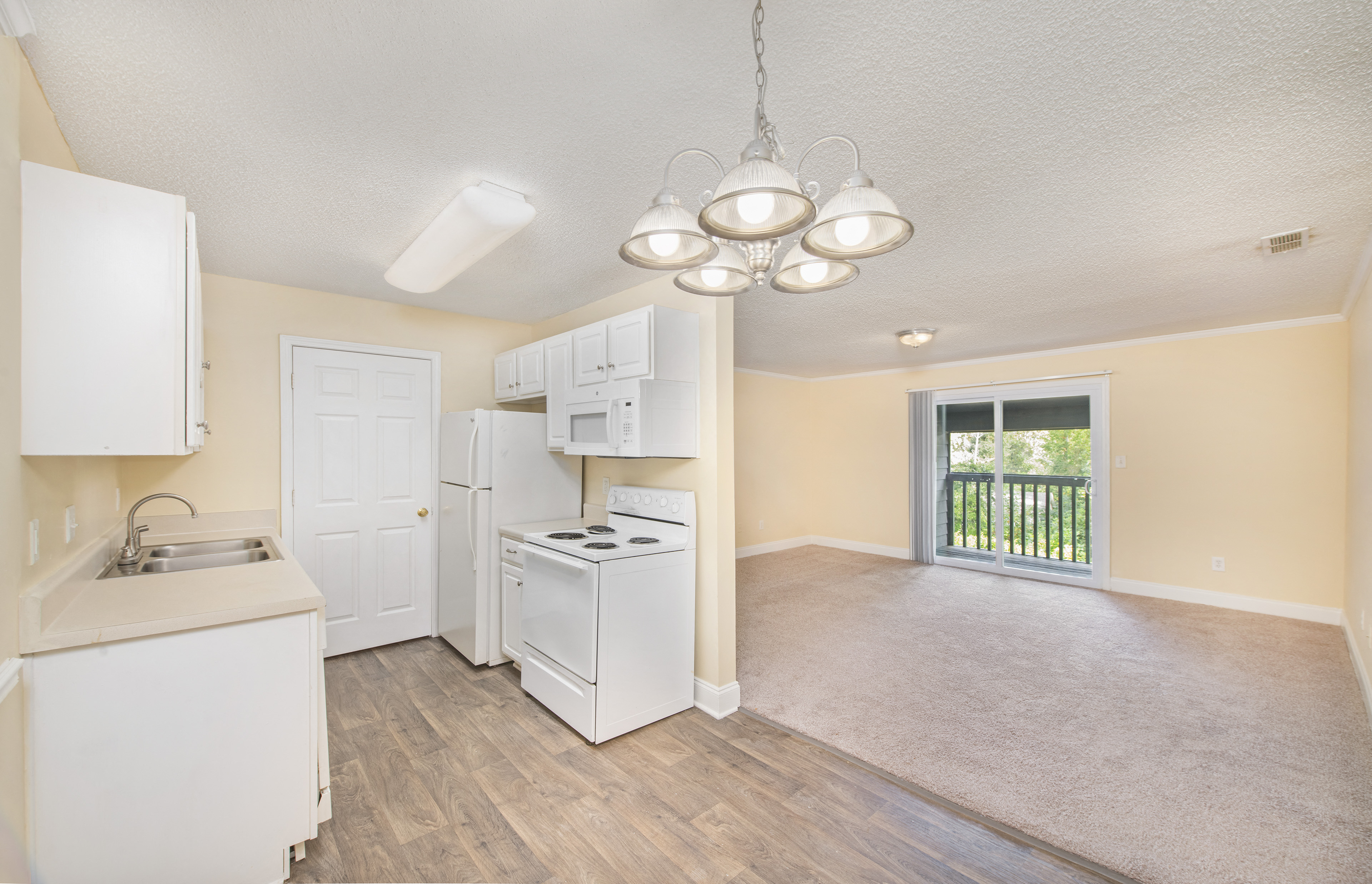 an empty kitchen and living room with white appliances and a window