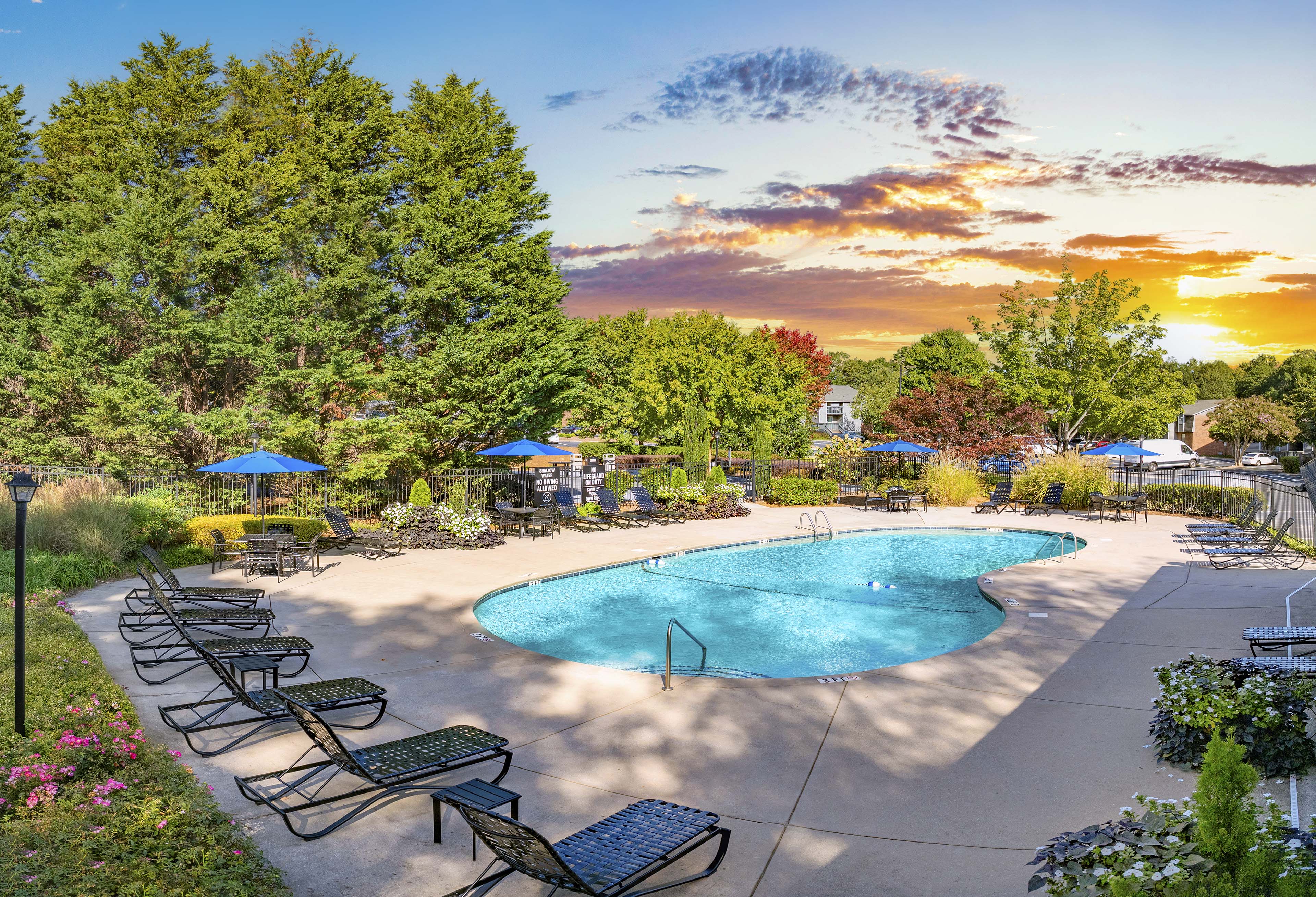 a swimming pool with chairs and umbrellas at sunset