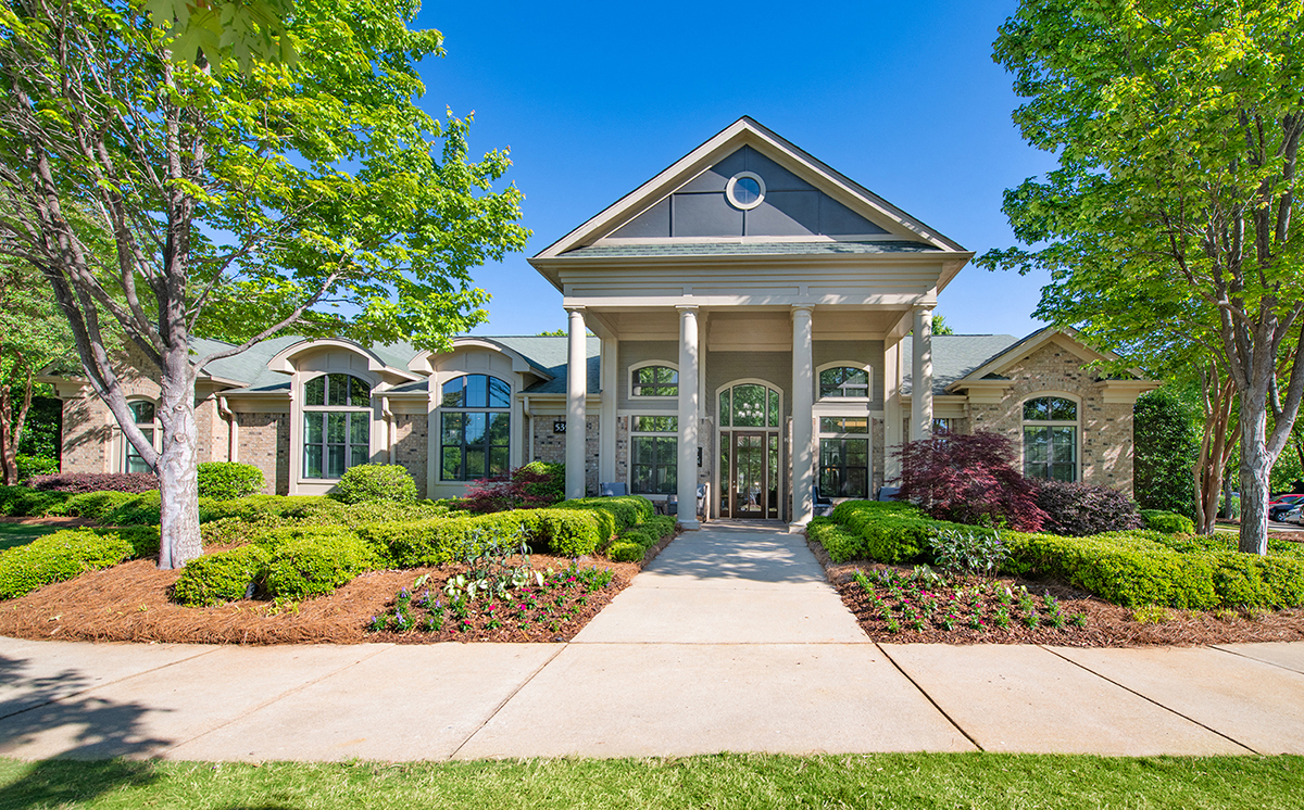 the front of a house with trees and a sidewalk