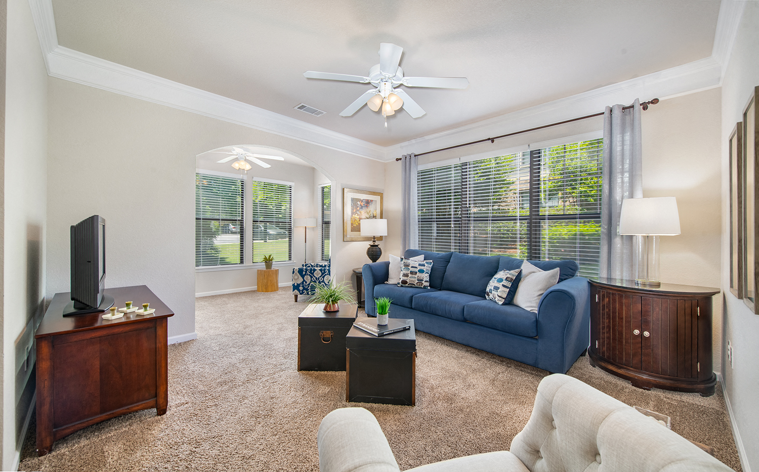 a living room with a blue couch and a ceiling fan