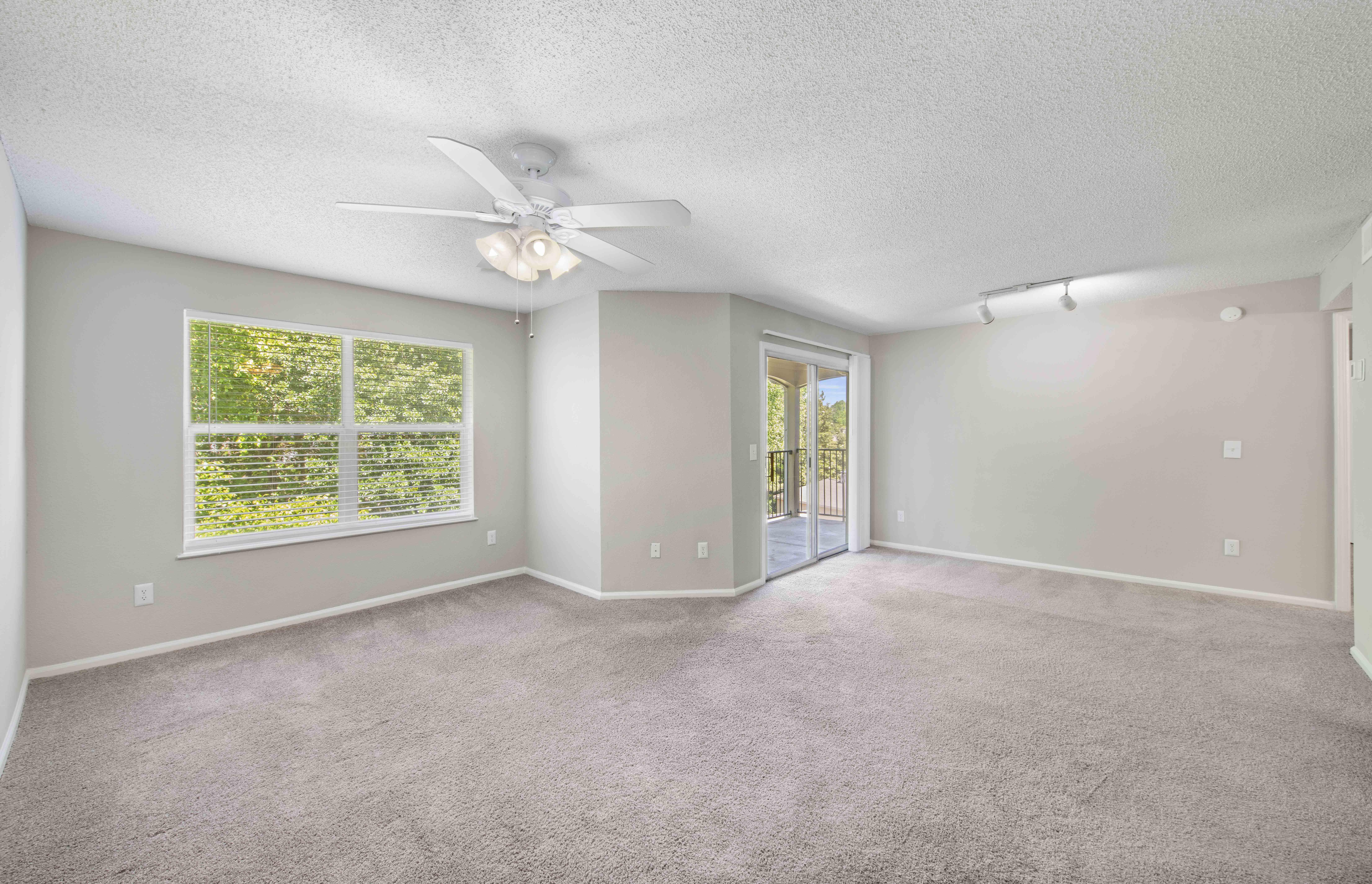 an empty living room with a ceiling fan and a window