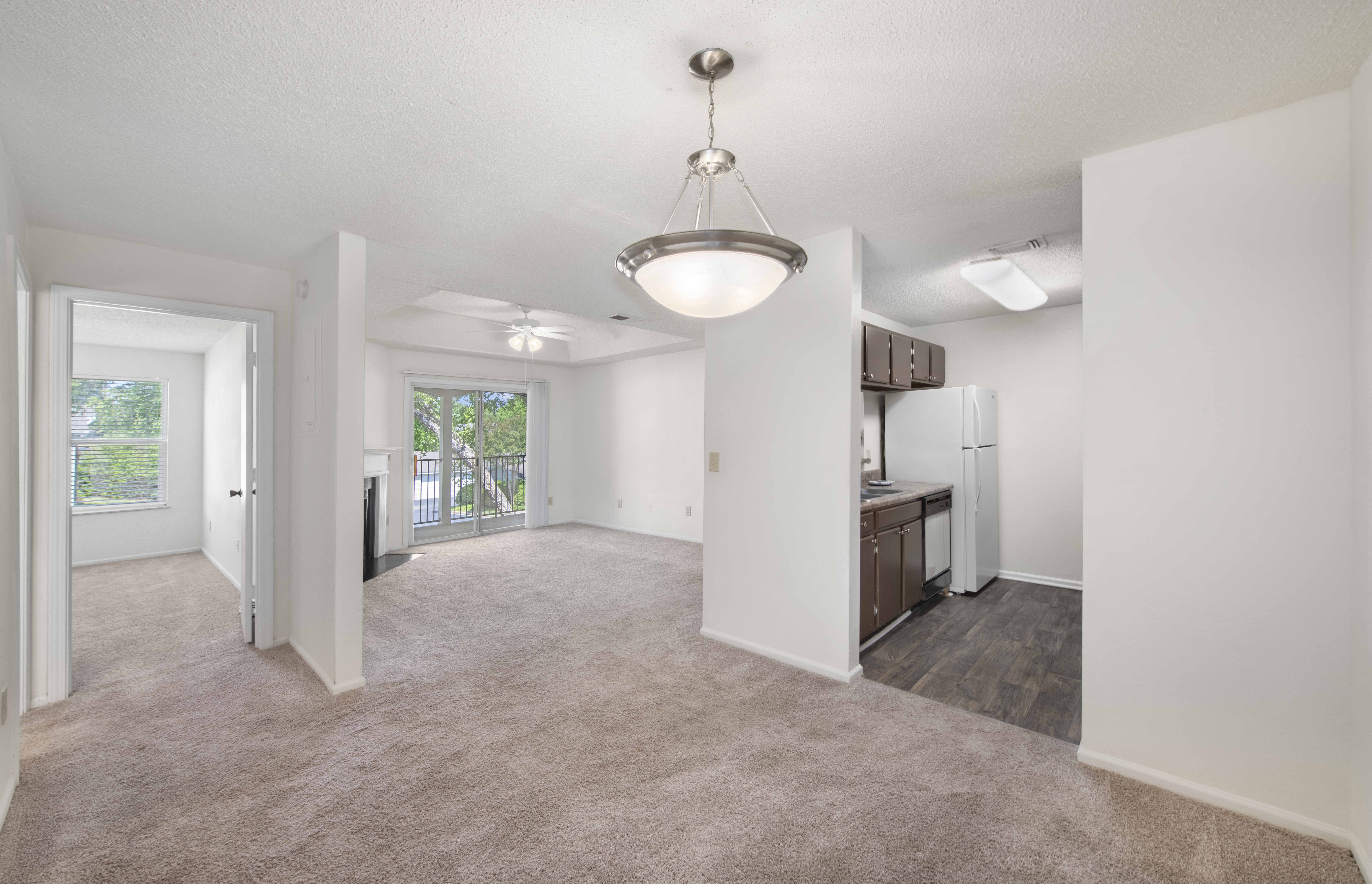 an empty living room and kitchen with a refrigerator and a sink