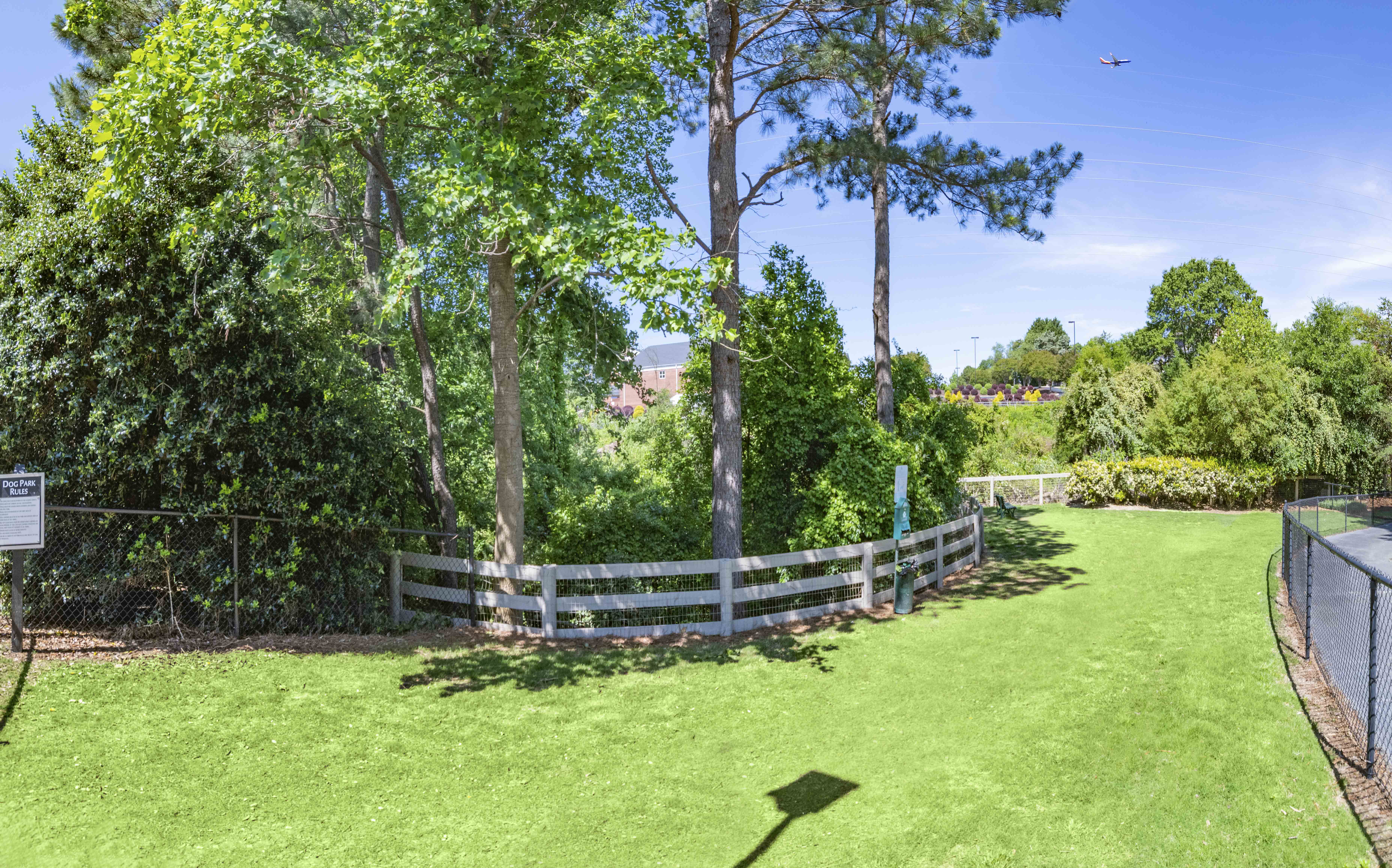 a backyard with a fence and a grass field and trees
