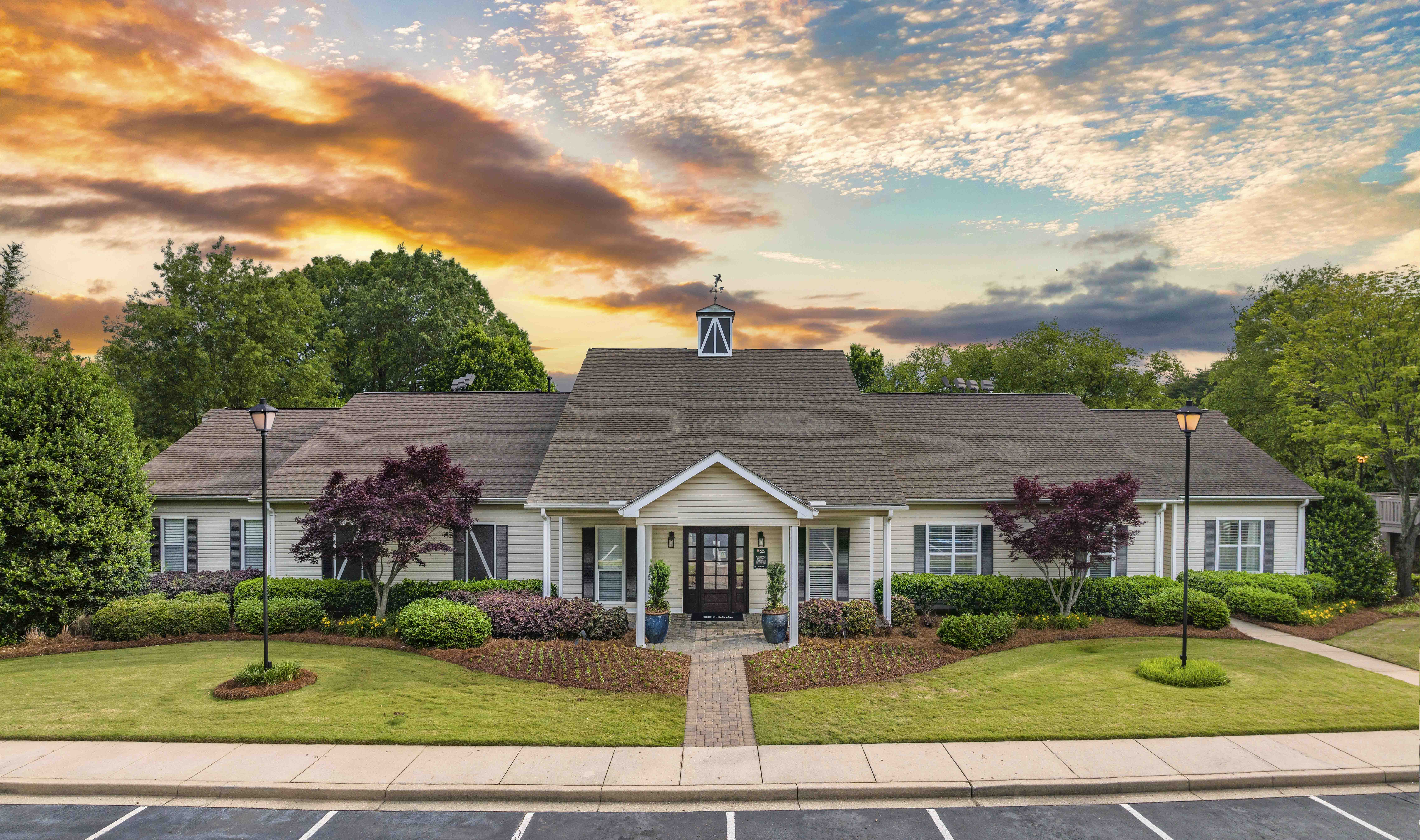 the front of a house with a lawn and trees