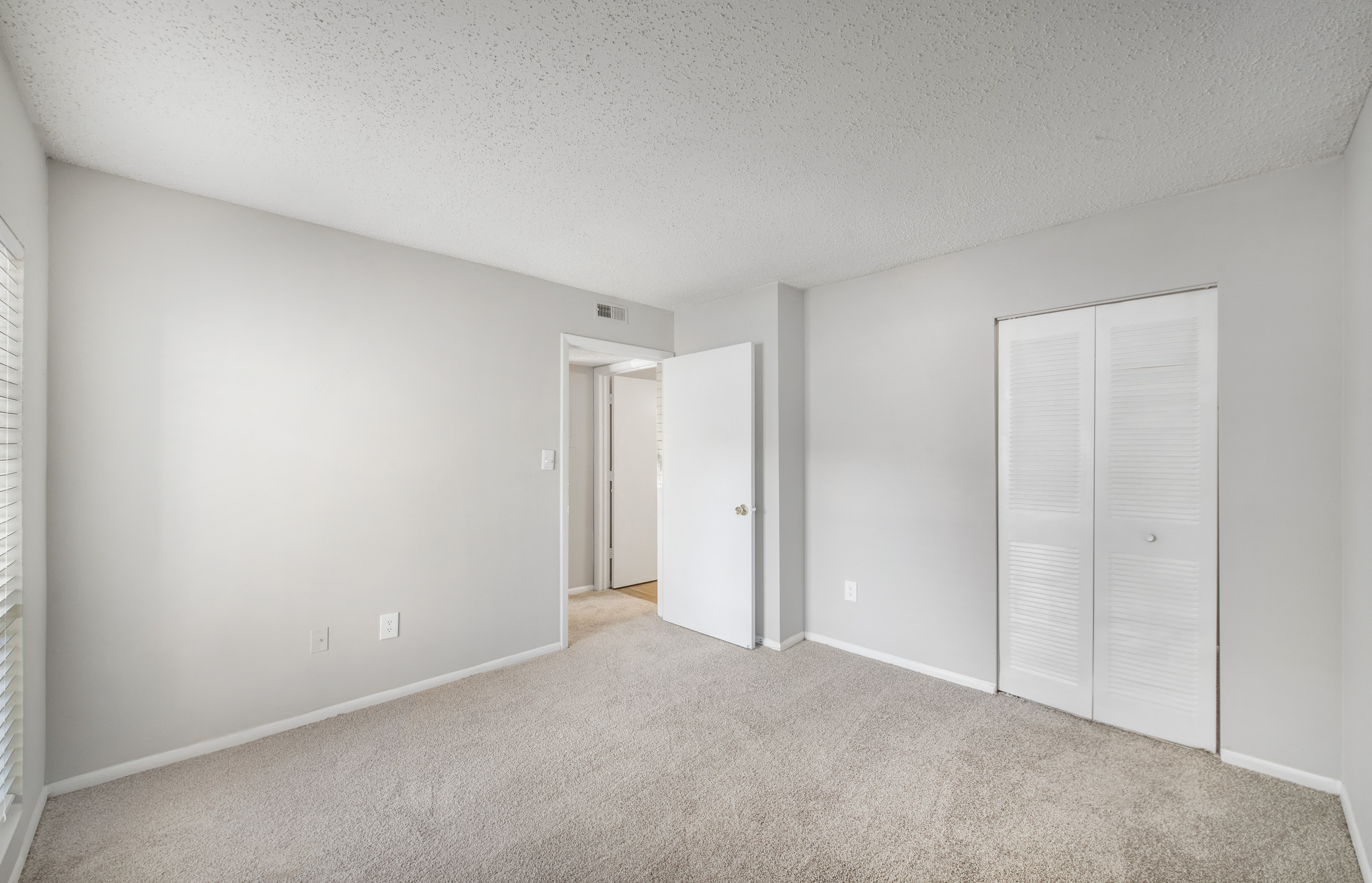 an empty living room with white walls and a door to a closet