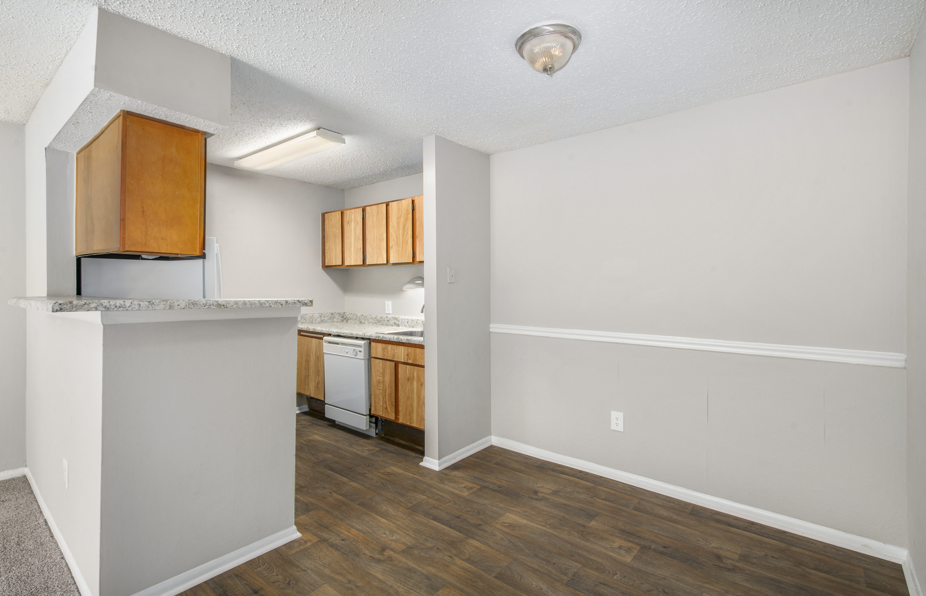 a kitchen and living room with a wood floor and white walls