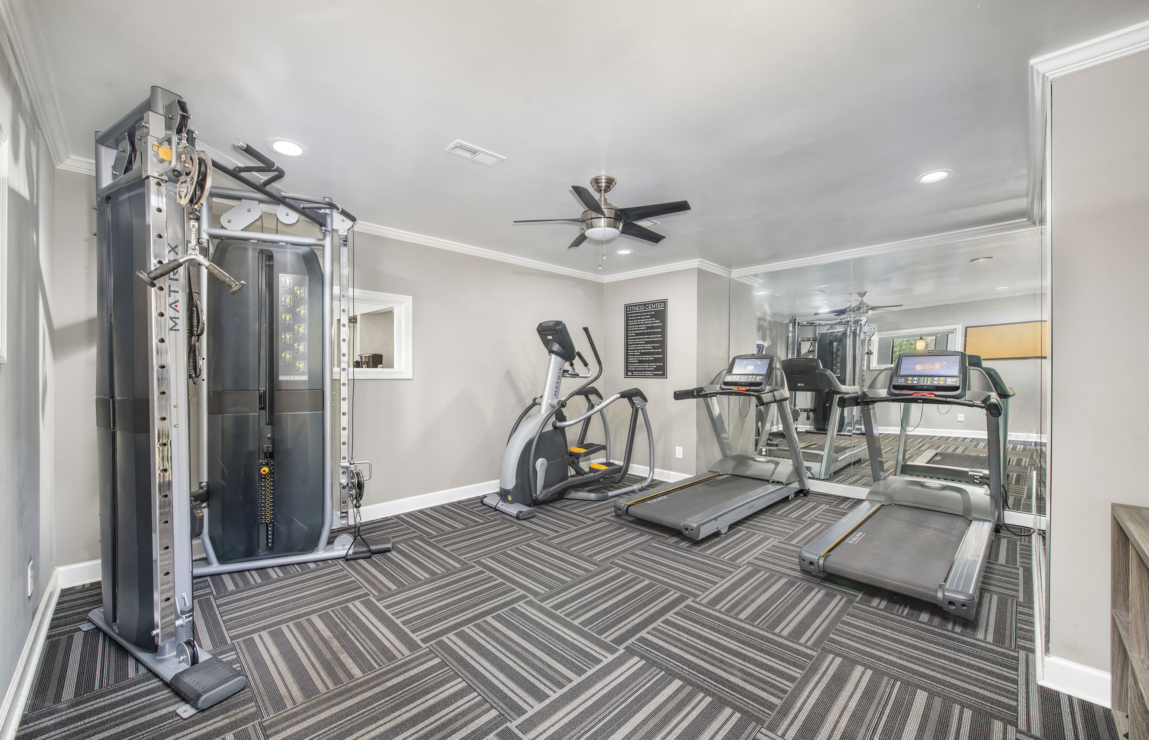 a gym with exercise machines and a ceiling fan