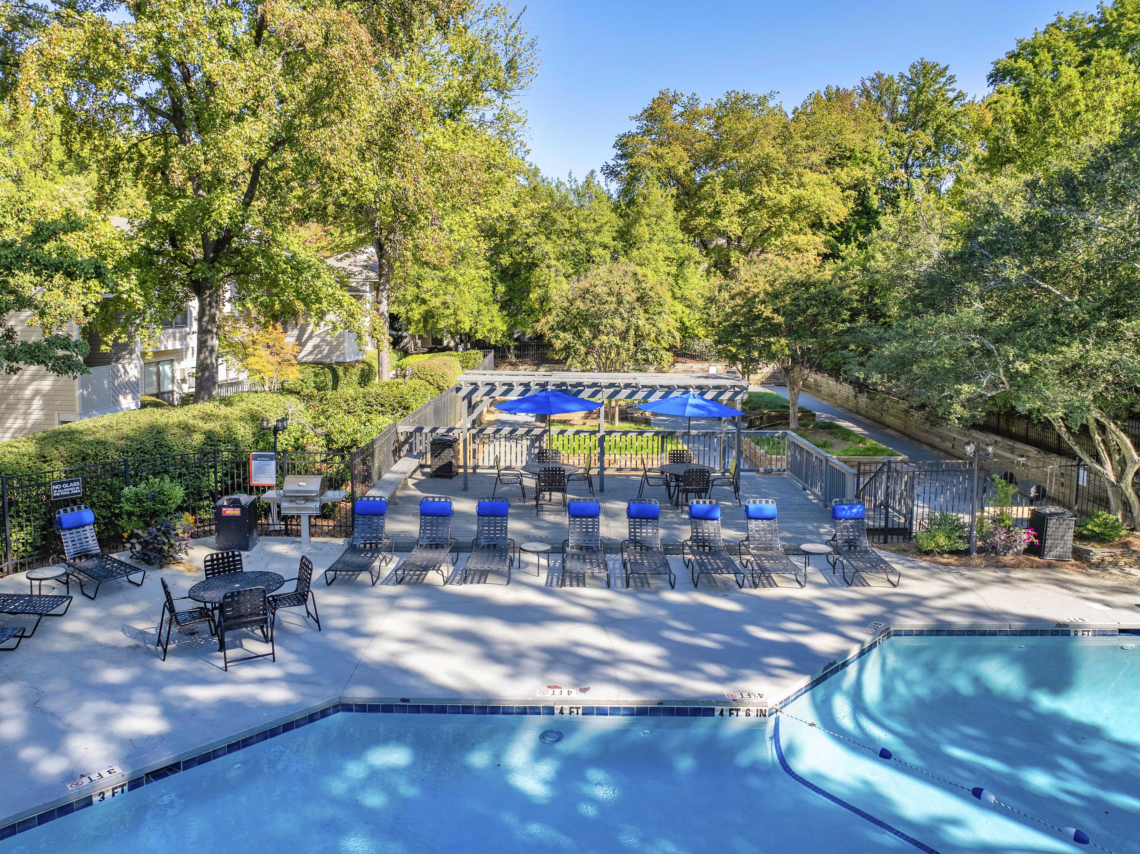 a backyard with a pool and patio with chairs and umbrellas