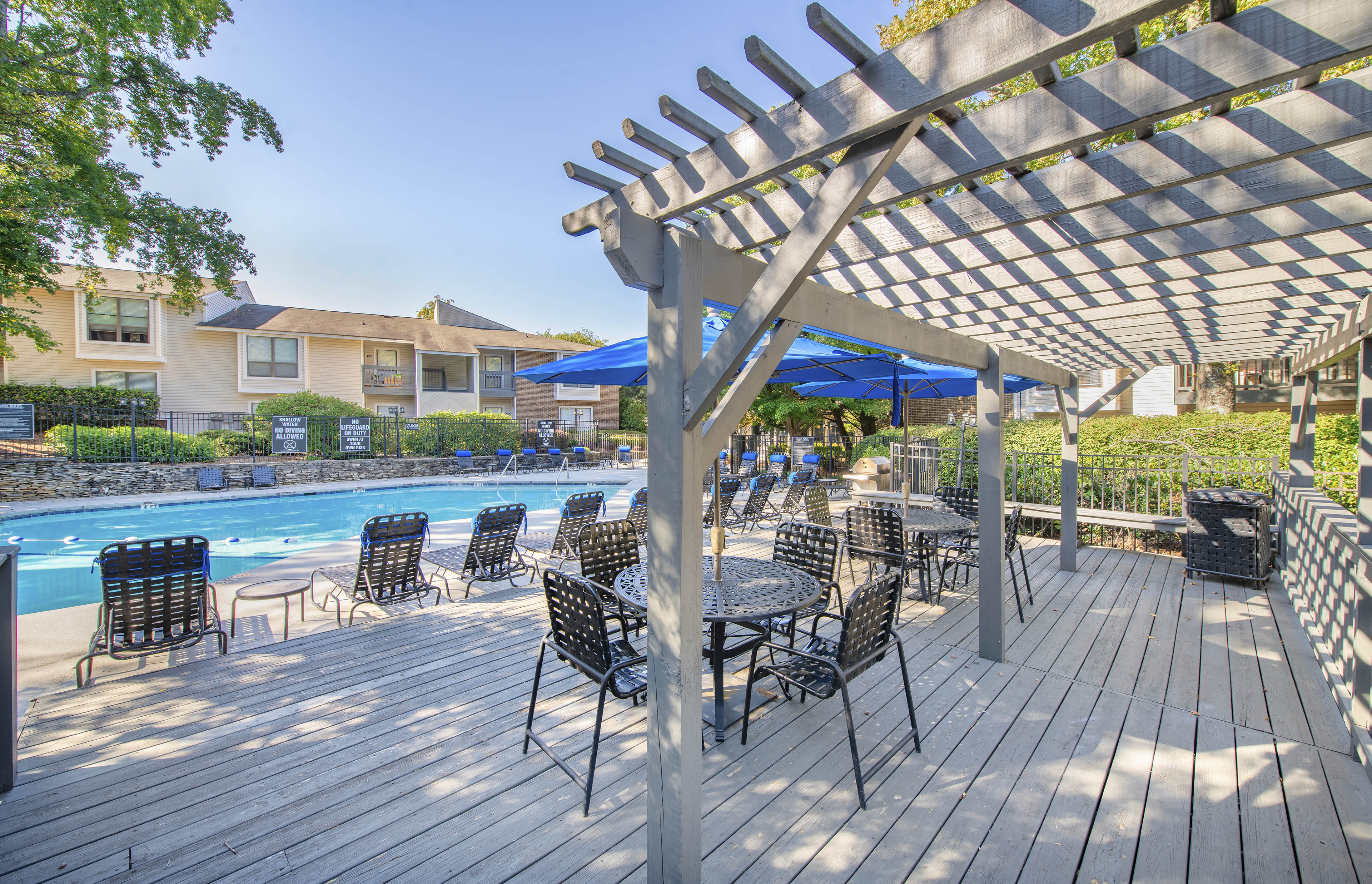 a covered patio with tables and chairs next to a swimming pool