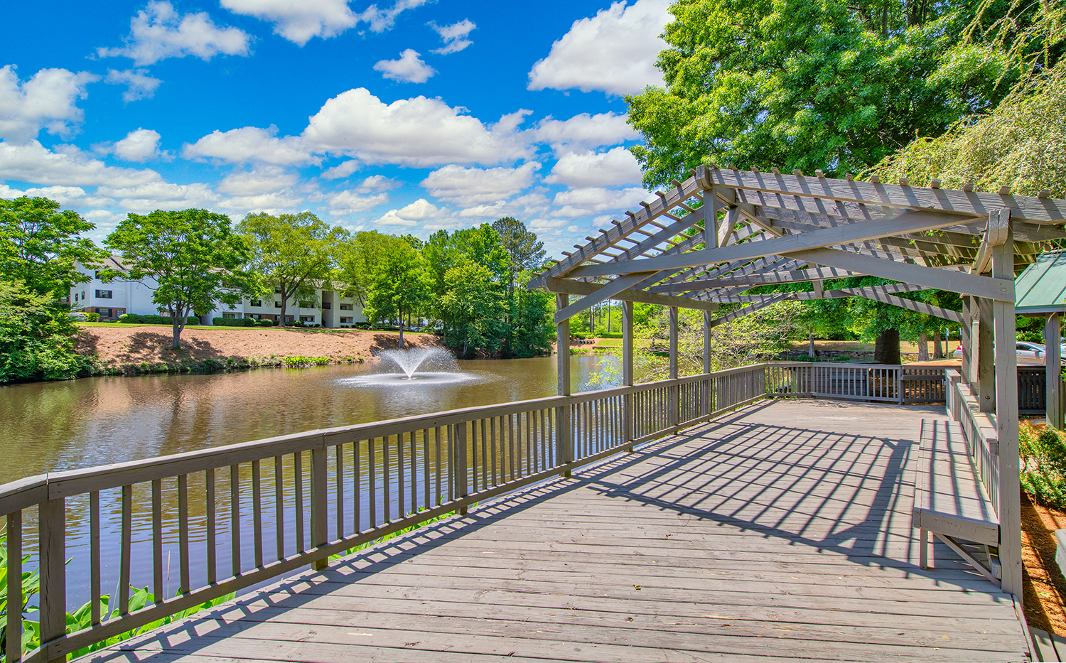 a boardwalk overlooking a pond with a fountain