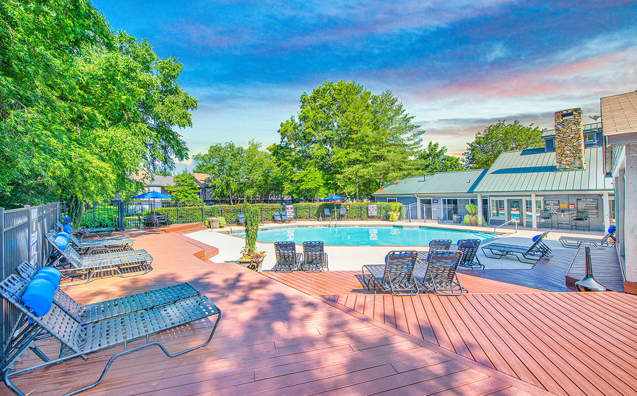 a swimming pool with lounge chairs on a wooden deck