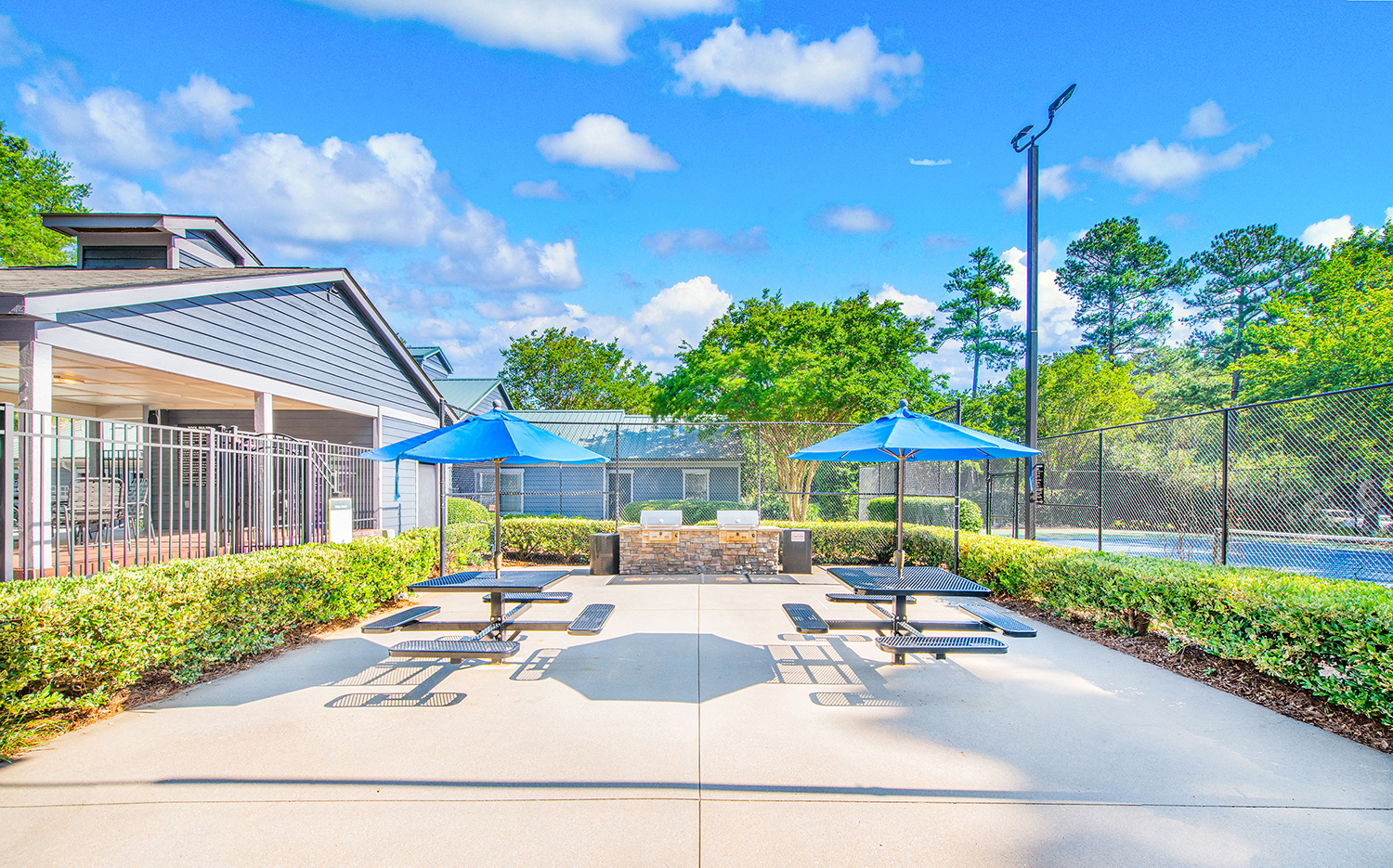a patio with picnic tables and umbrellas outside of a building with a pool