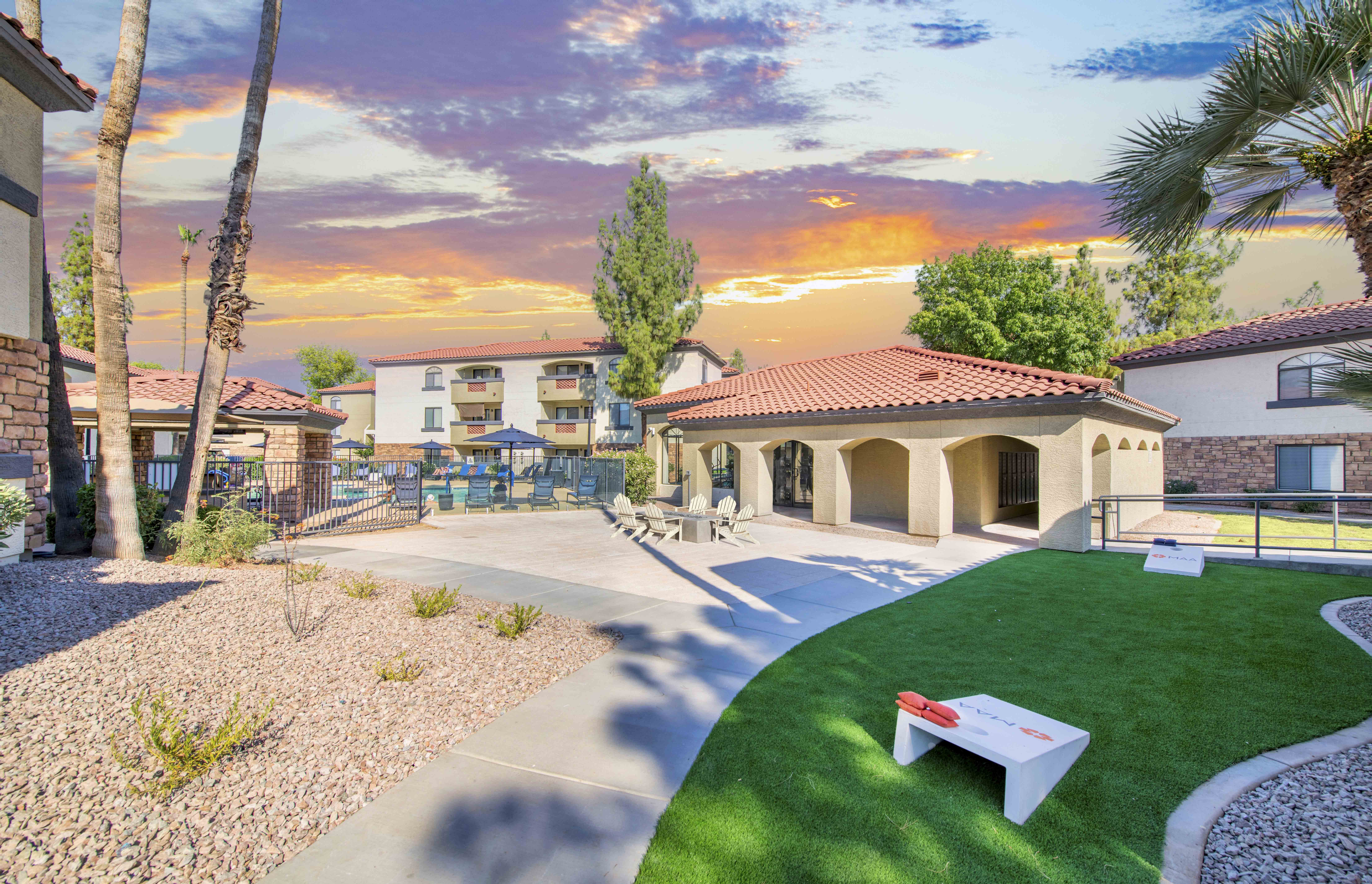 a yard with a picnic table and a building with palm trees