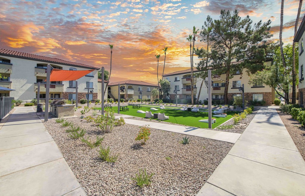 a courtyard with trees and buildings at sunset