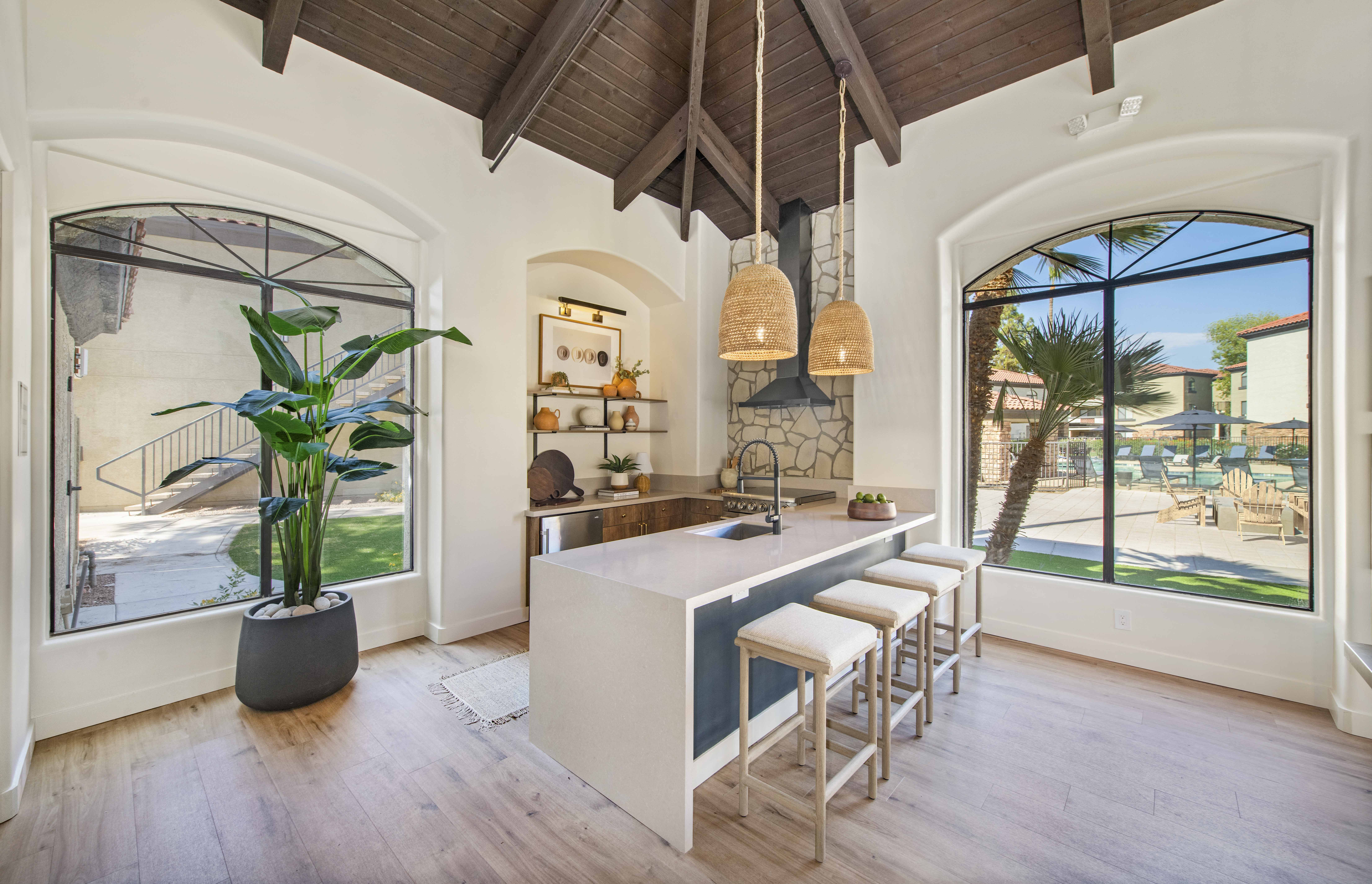 a kitchen with a long island with stools and large windows