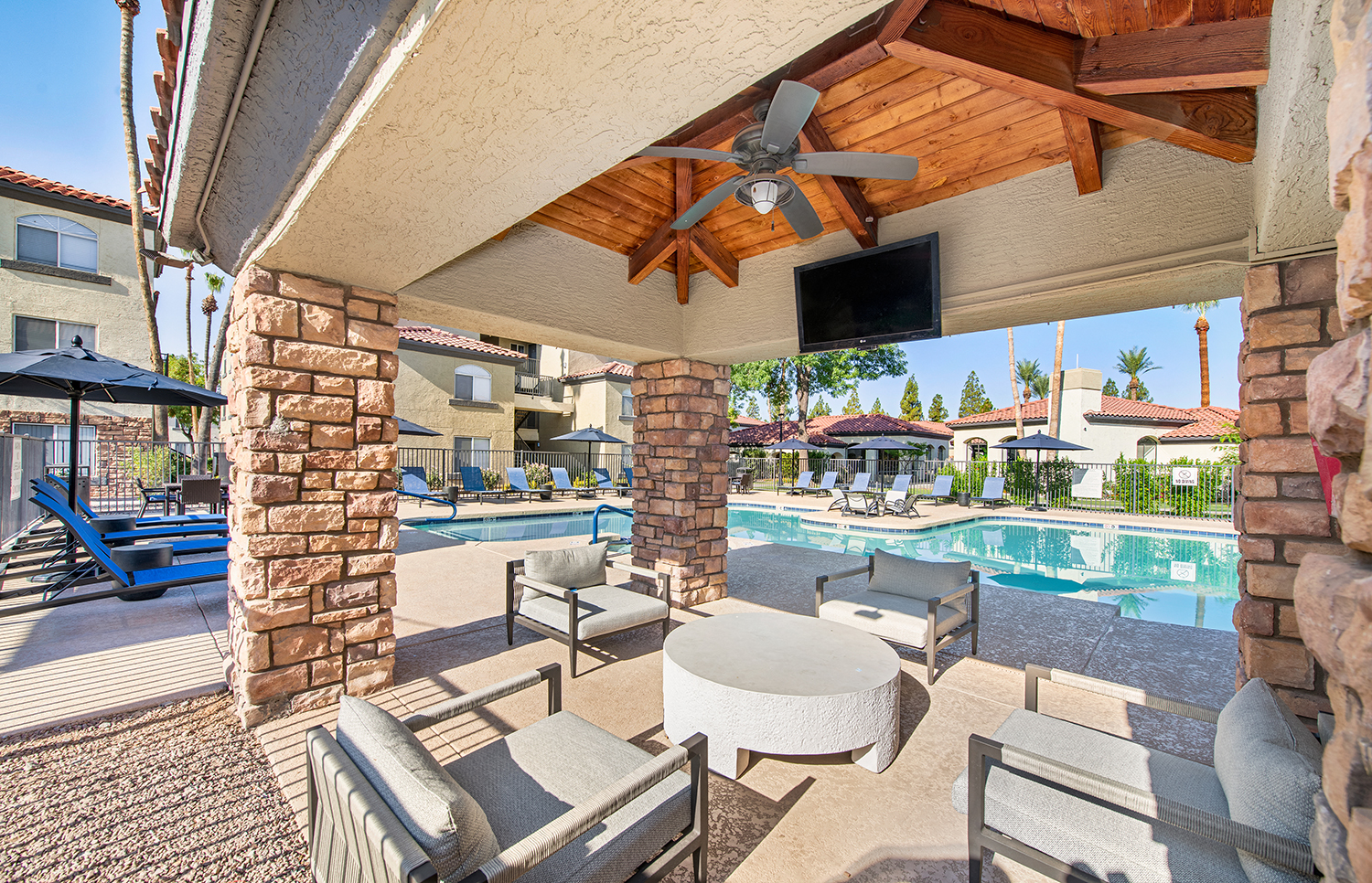 a patio with a pool and chairs and a ceiling fan