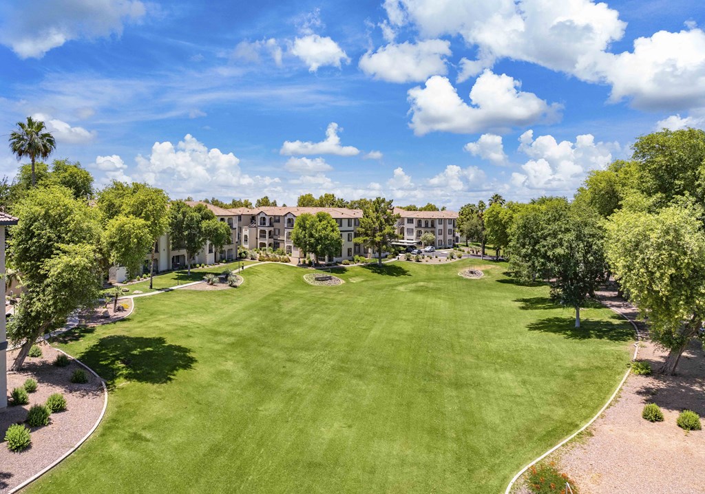 an aerial view of a lush green park with apartments in the background