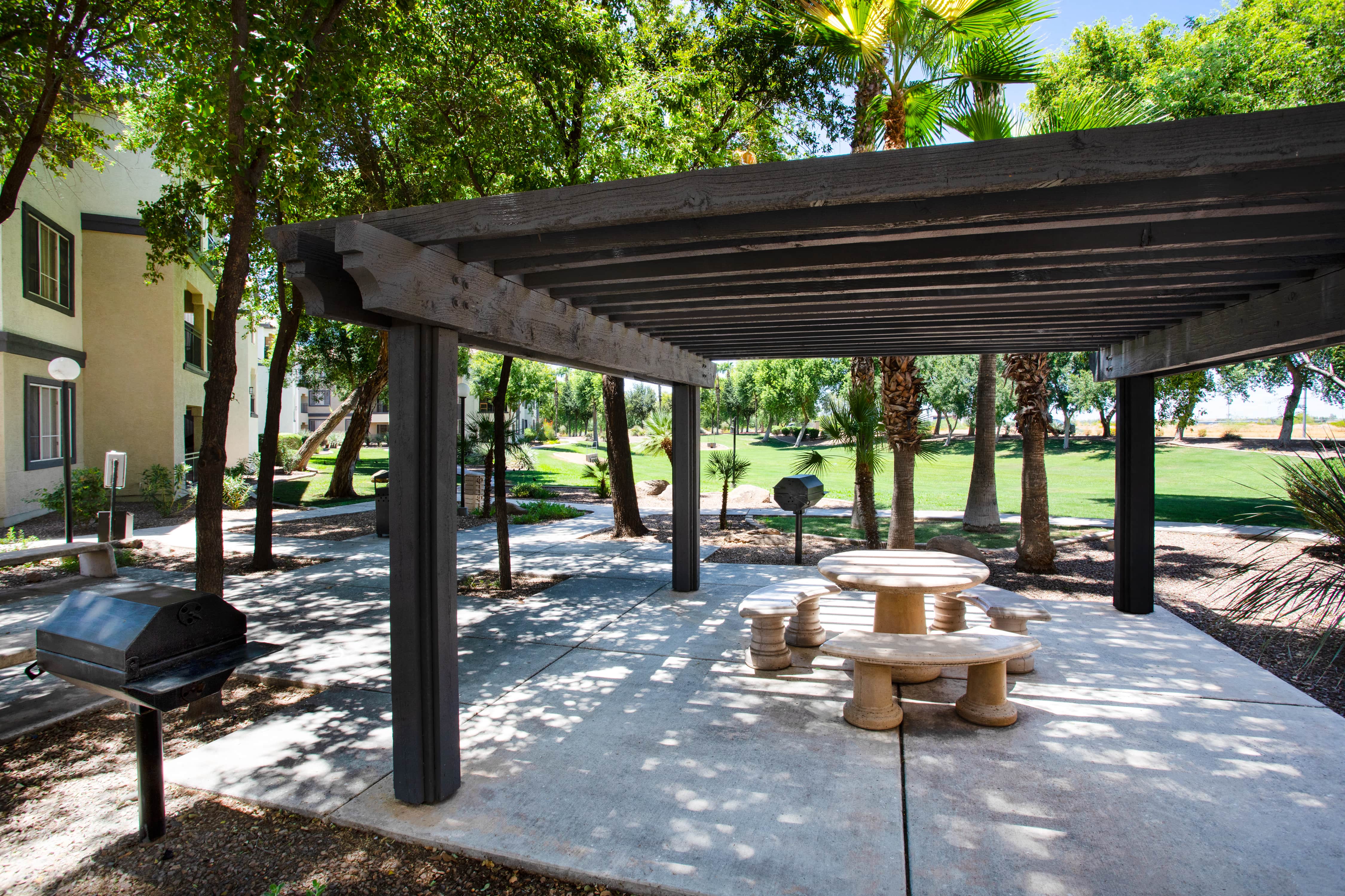 a patio with a picnic table and a grill