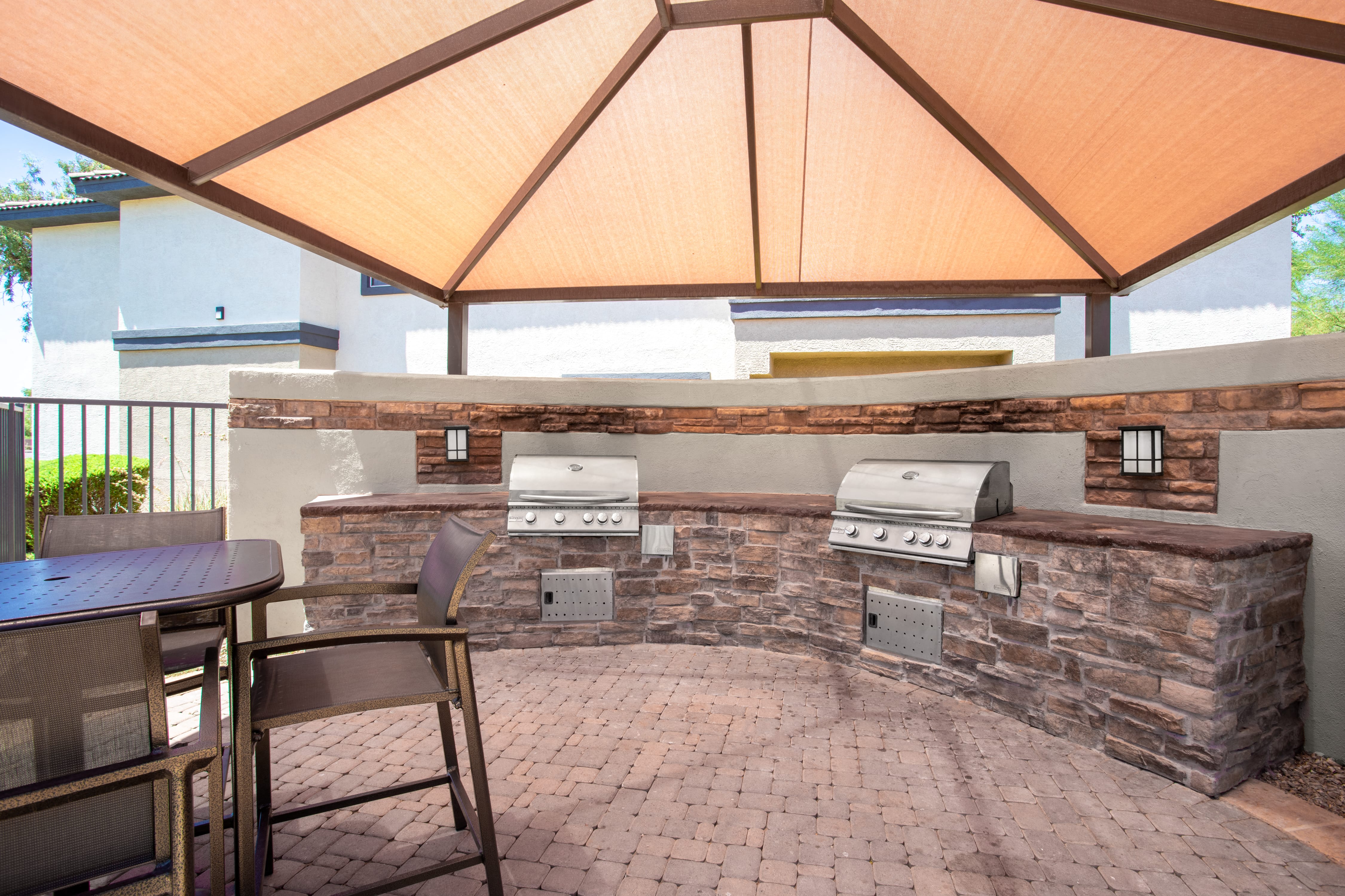 a covered patio with a grill and a table with chairs