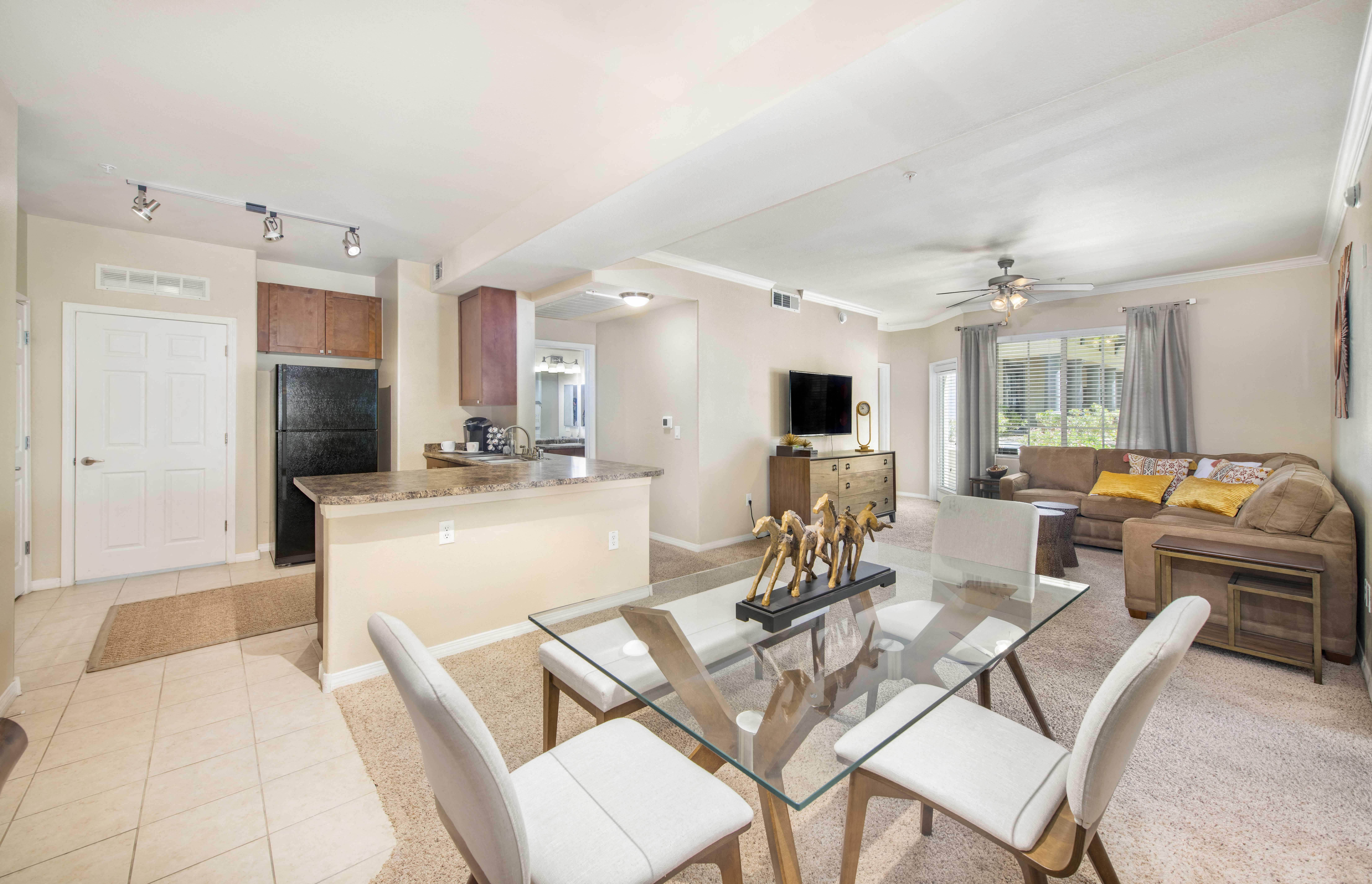 a living room and kitchen with a glass table and chairs