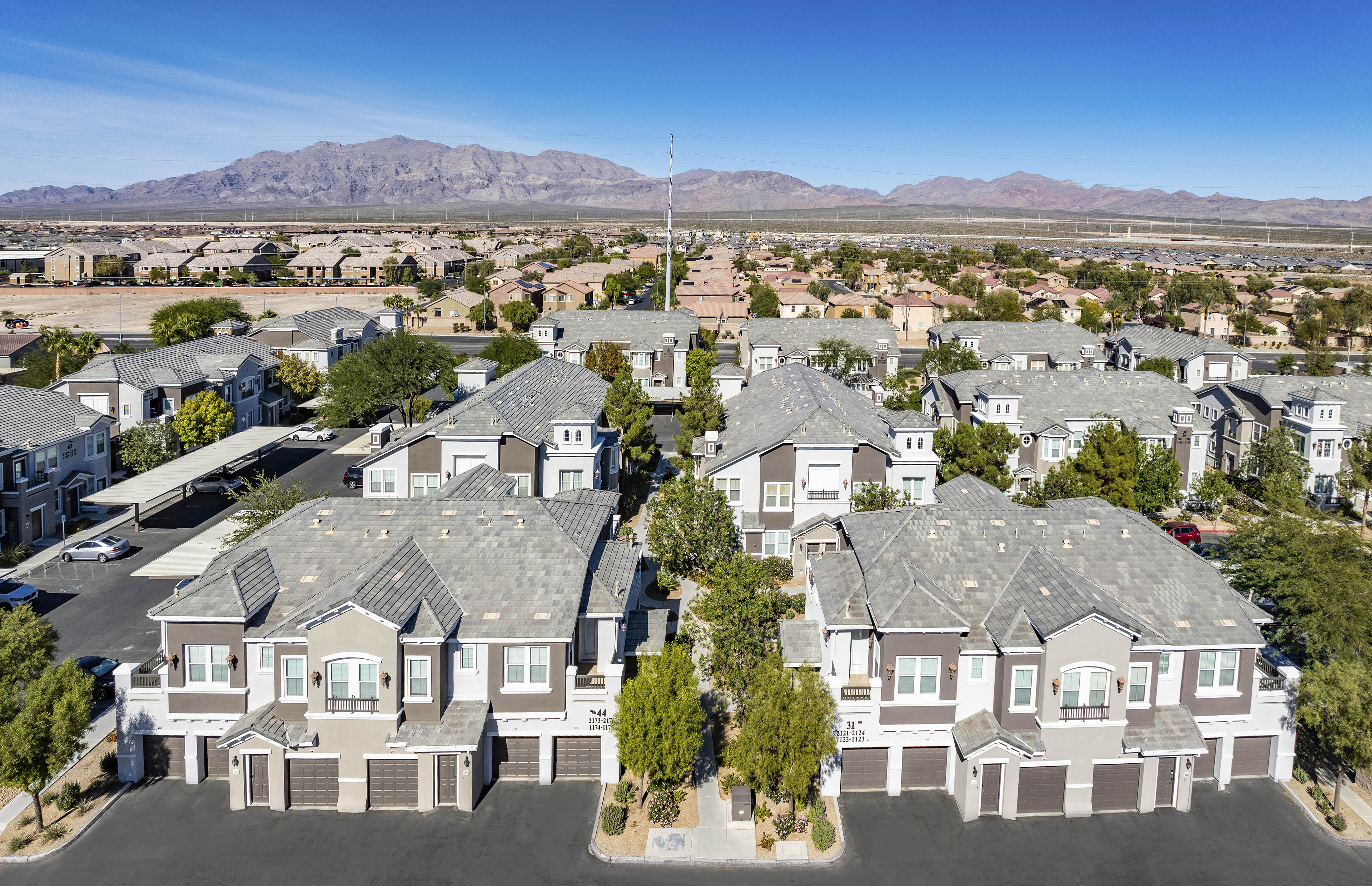 an aerial view of a neighborhood of houses with mountains in the background