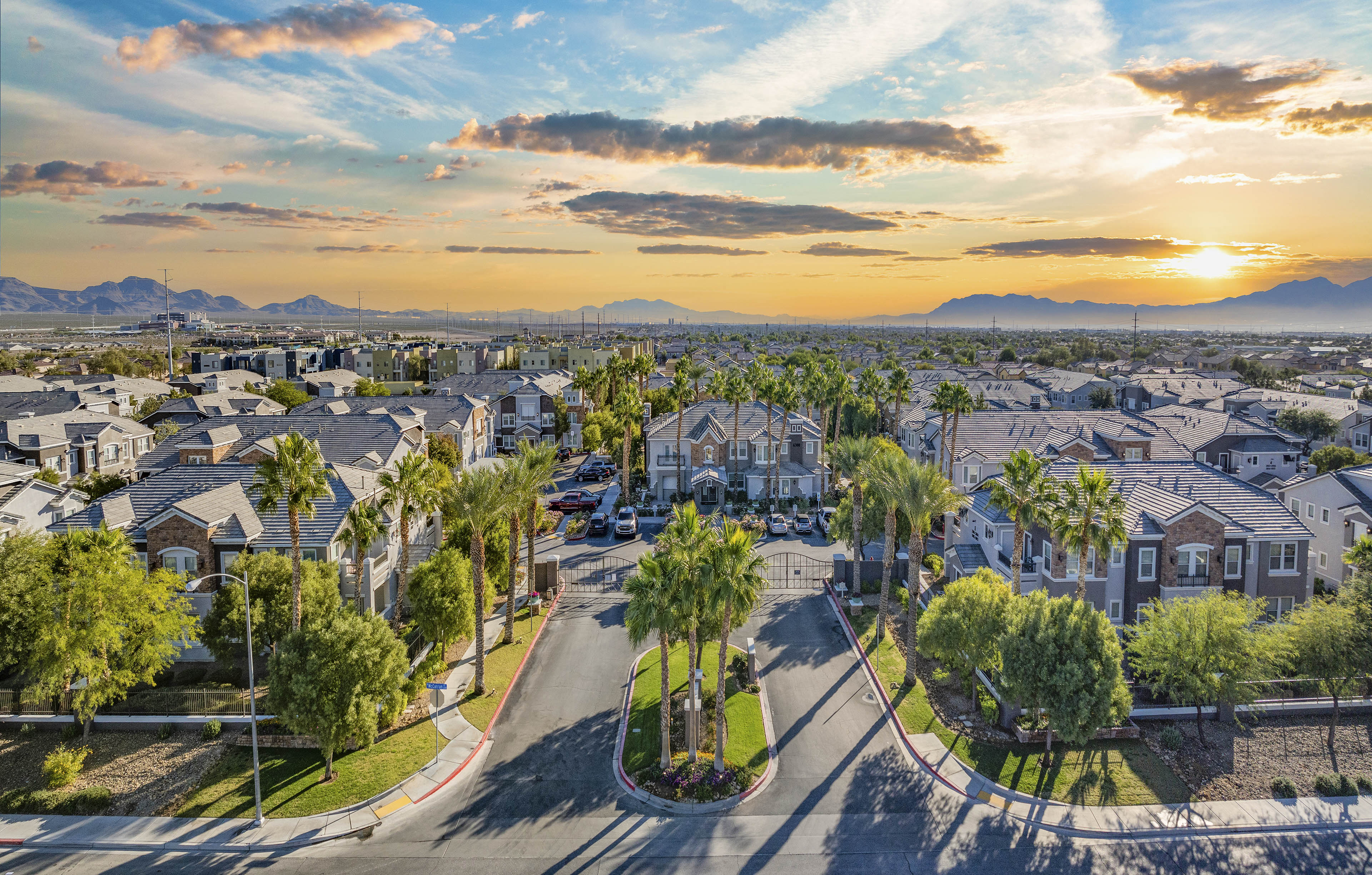 a sunset over a neighborhood of houses with palm trees