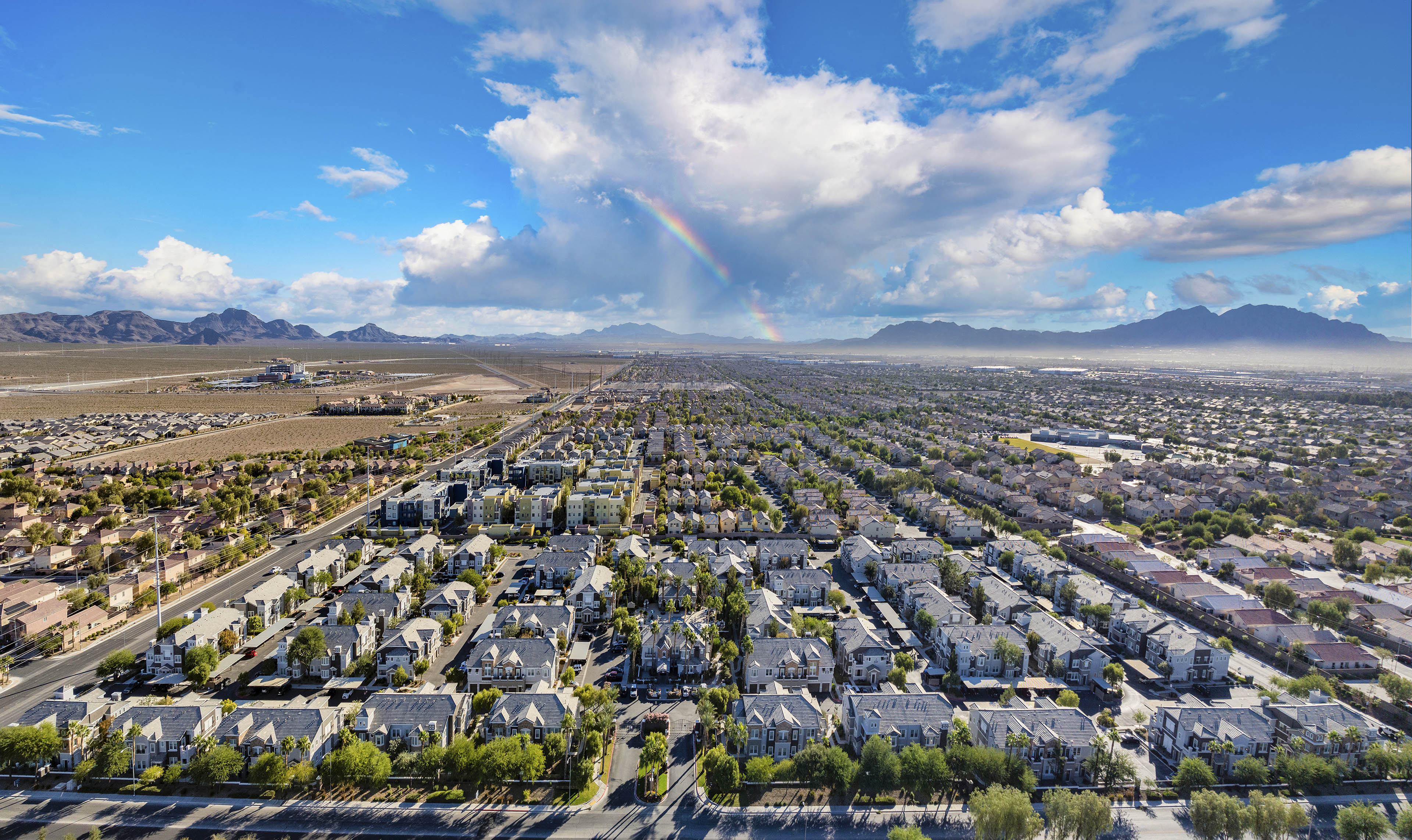 an aerial view of a city with a rainbow in the sky