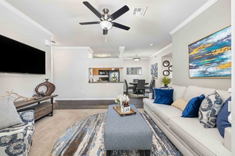 A living room with a grey sofa, a coffee table, and a ceiling fan.