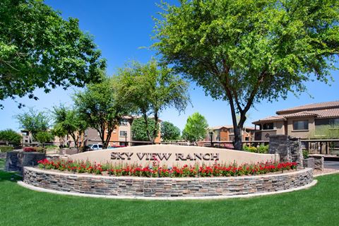 a sign for sky view ranch with trees and a building in the background