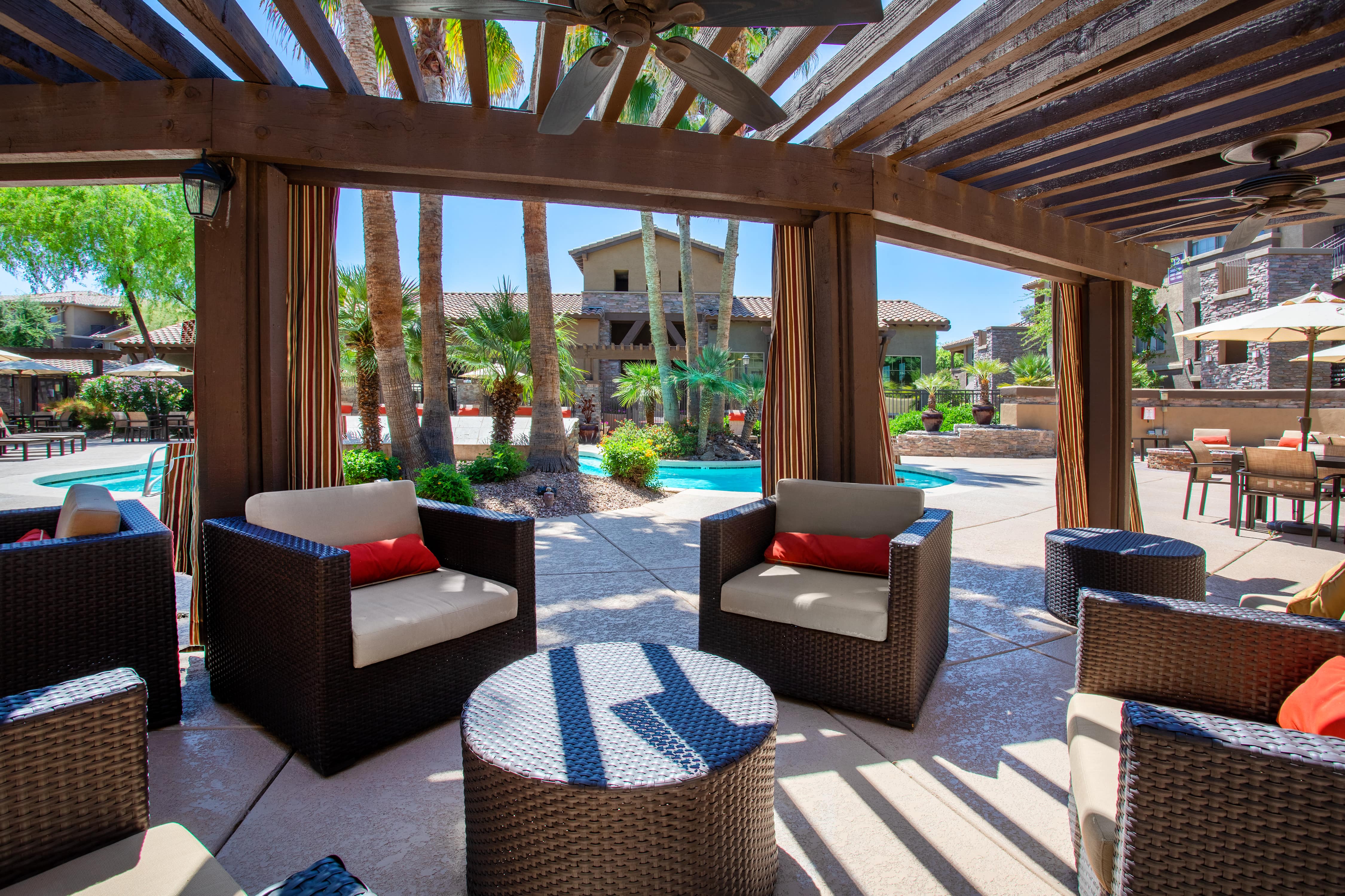 a covered patio with chairs and tables and a pool