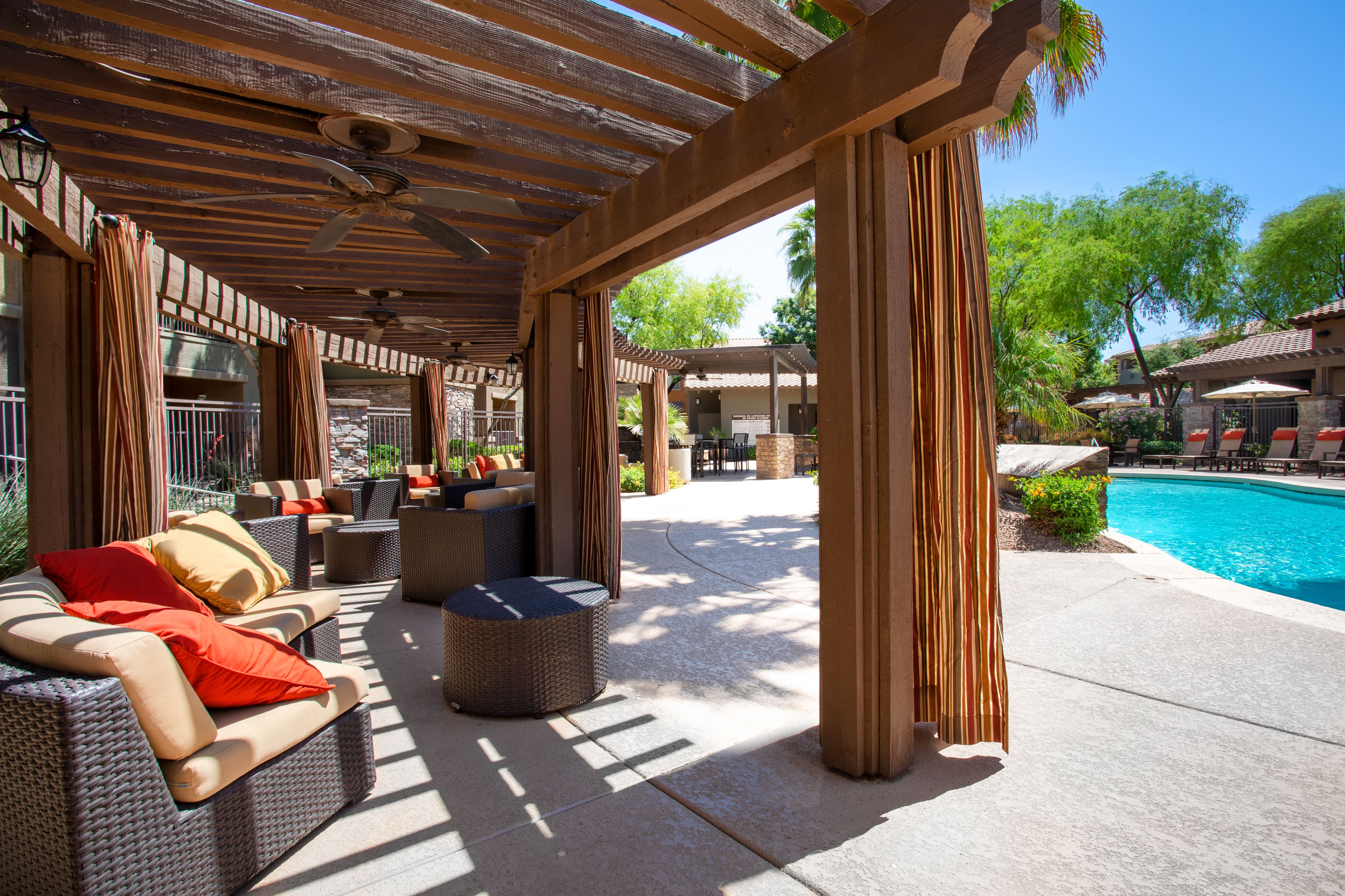 a covered patio with chairs and a swimming pool