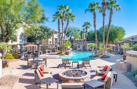A pool surrounded by palm trees and patio furniture.