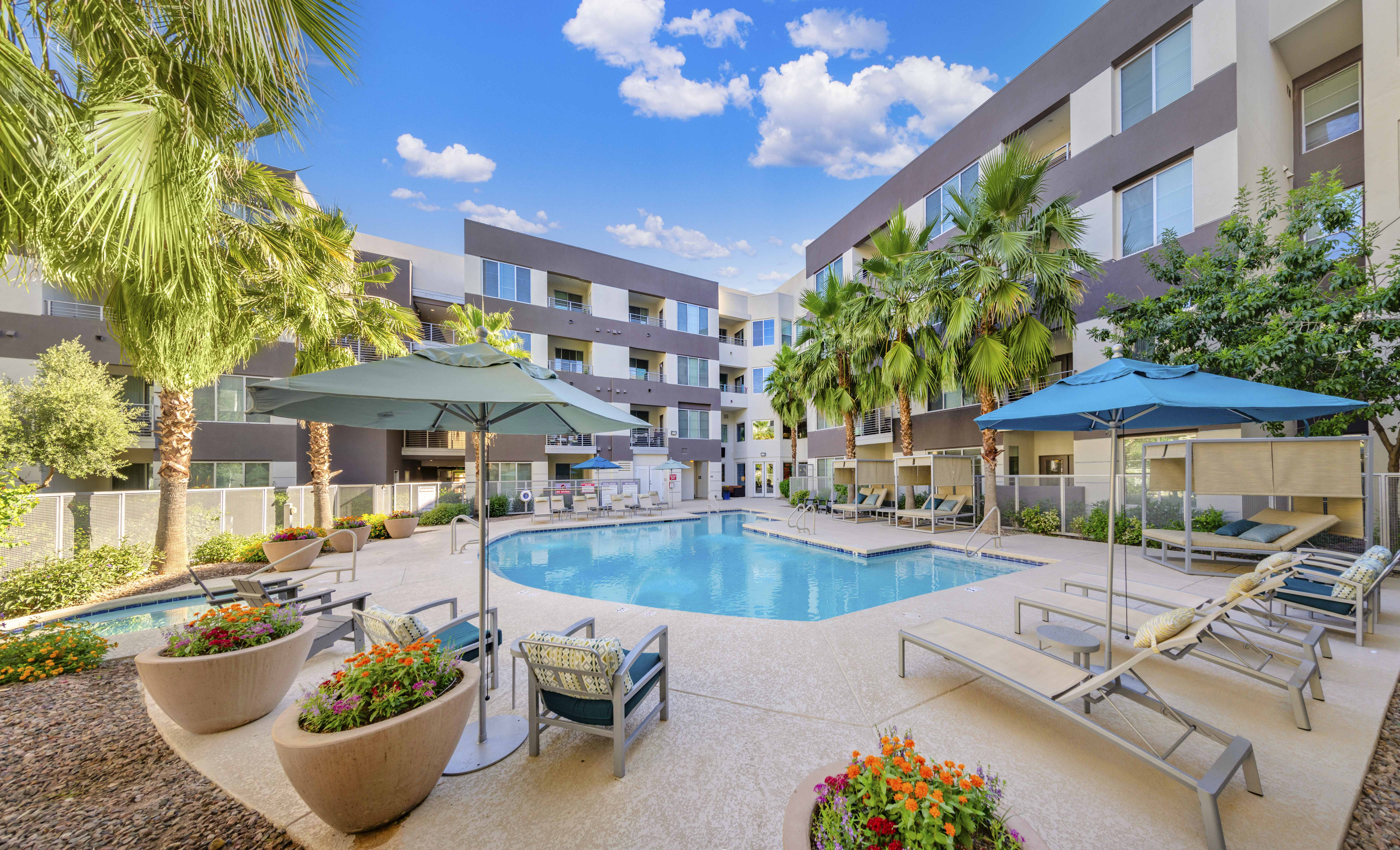a swimming pool with chairs and umbrellas in front of a building