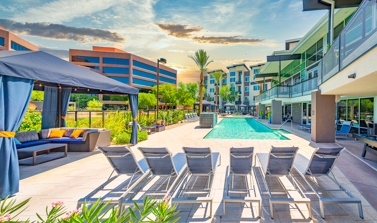 a pool with lounge chairs and umbrellas next to a building