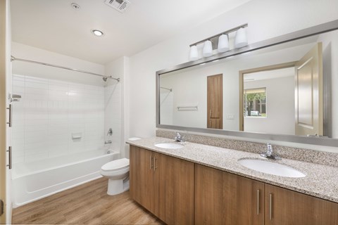 A bathroom with a white tub, sink, and mirror.