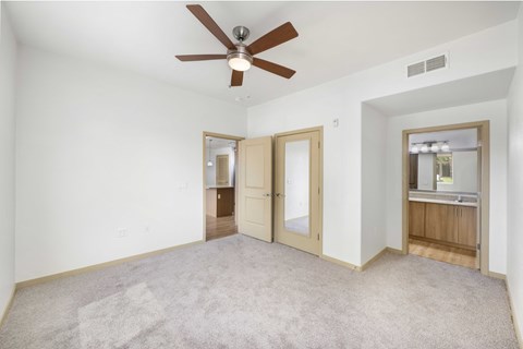 A room with a ceiling fan and carpeted floor.