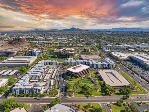 A cityscape with buildings and roads under a colorful sky.