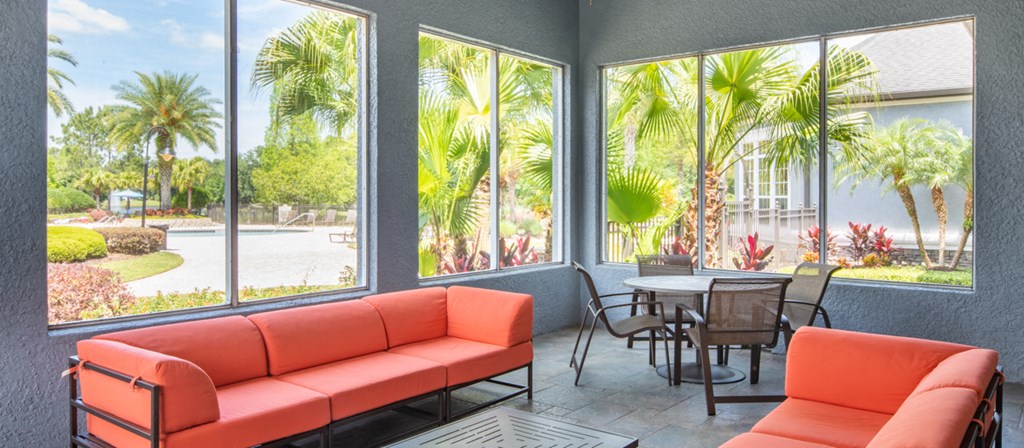 a patio with orange couches and a table and chairs