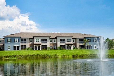 an apartment building overlooking a lake with a fountain