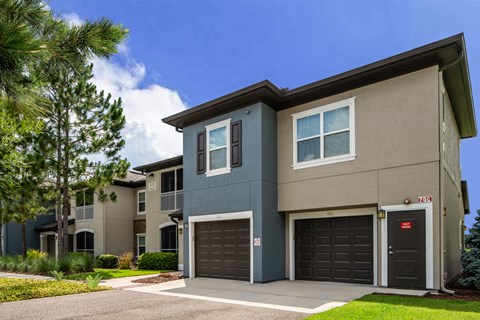 an apartment building with a driveway and two garage doors