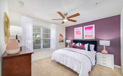 A bedroom with a bed, nightstand, and a ceiling fan.