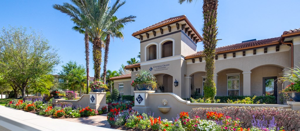 a building with palm trees and flowers in front of it