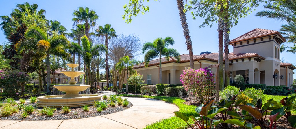 a fountain in the center of a garden in front of a building
