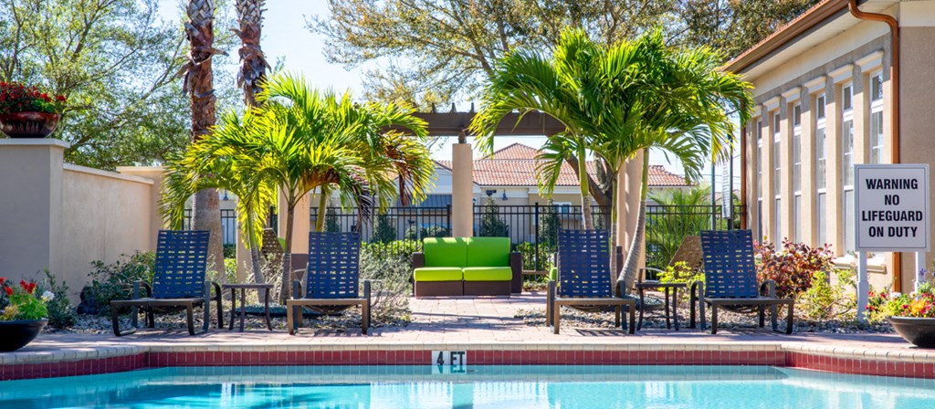 a swimming pool with blue chairs and palm trees next to a building